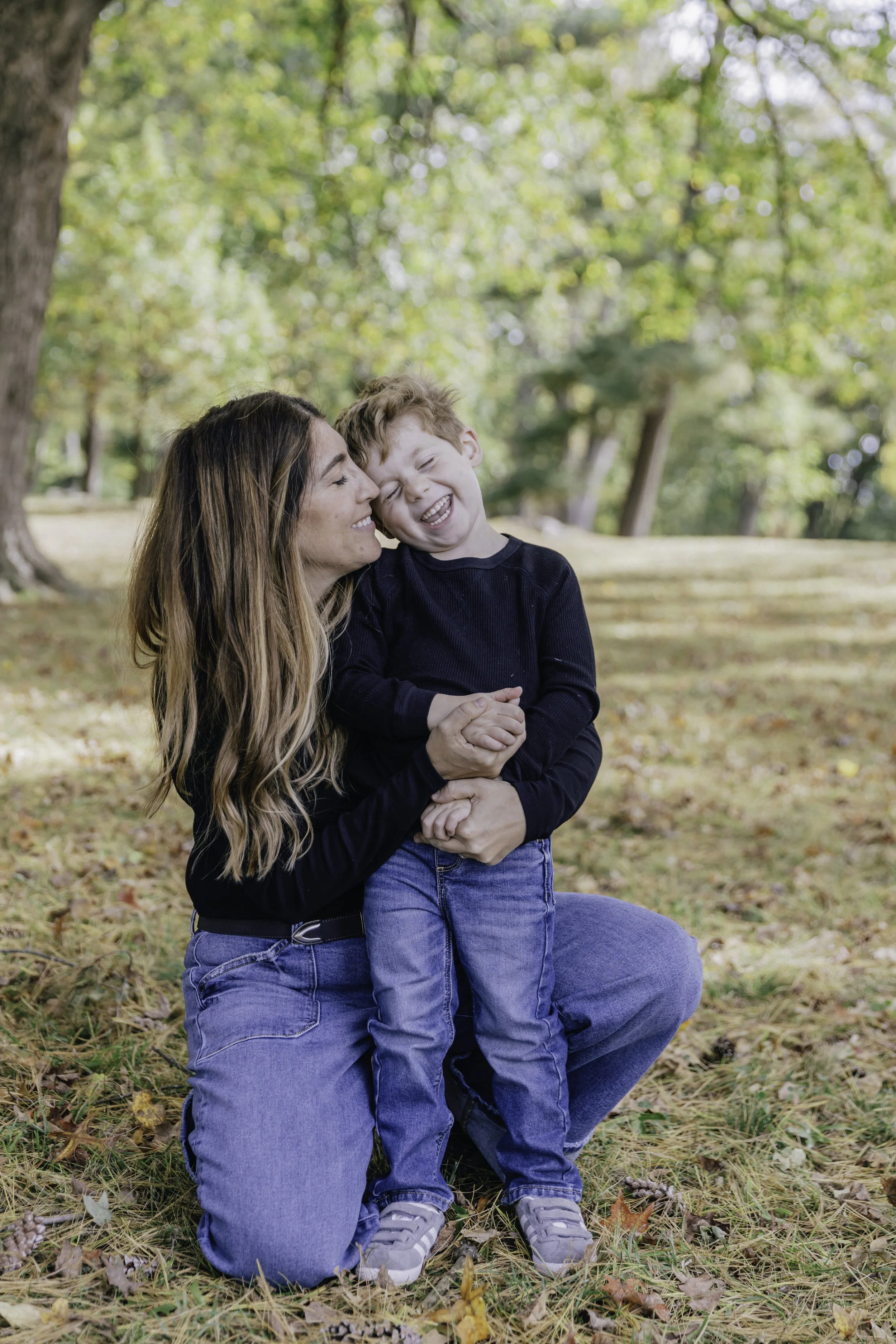 Woman kneeling holding young boy outdoors — NYC family photography