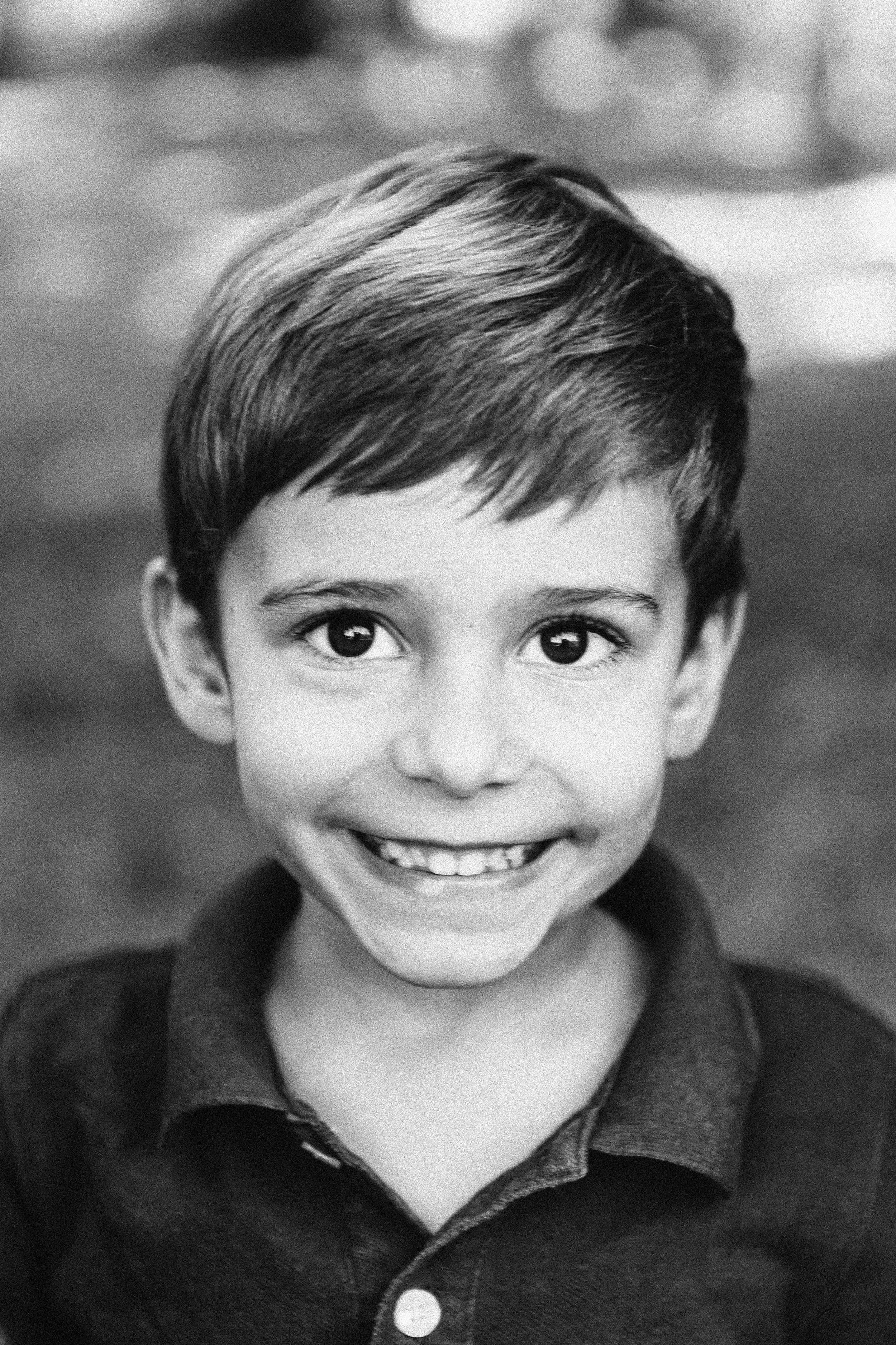 Close-up black and white photo of smiling young boy with short hair, wearing a collared shirt.