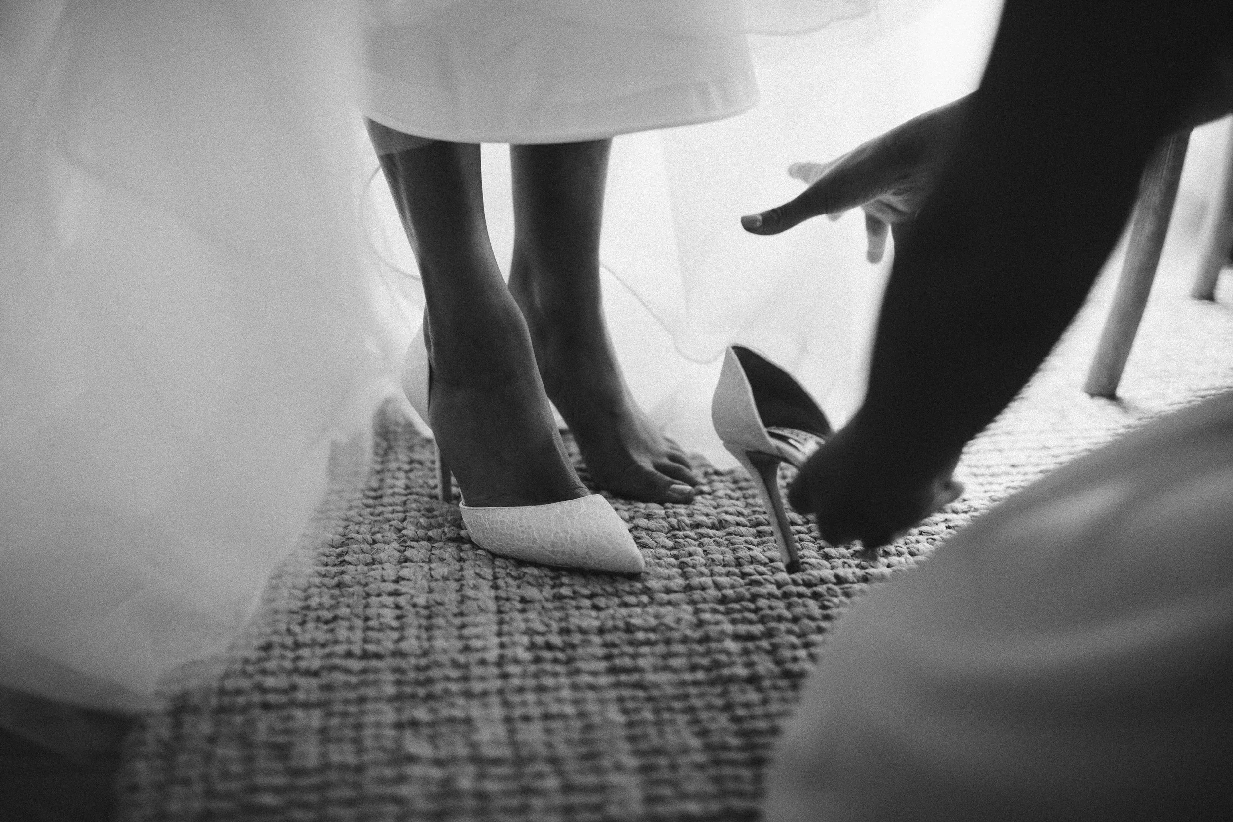 Close-up of a woman helping another woman put on high heels New York City wedding photographer