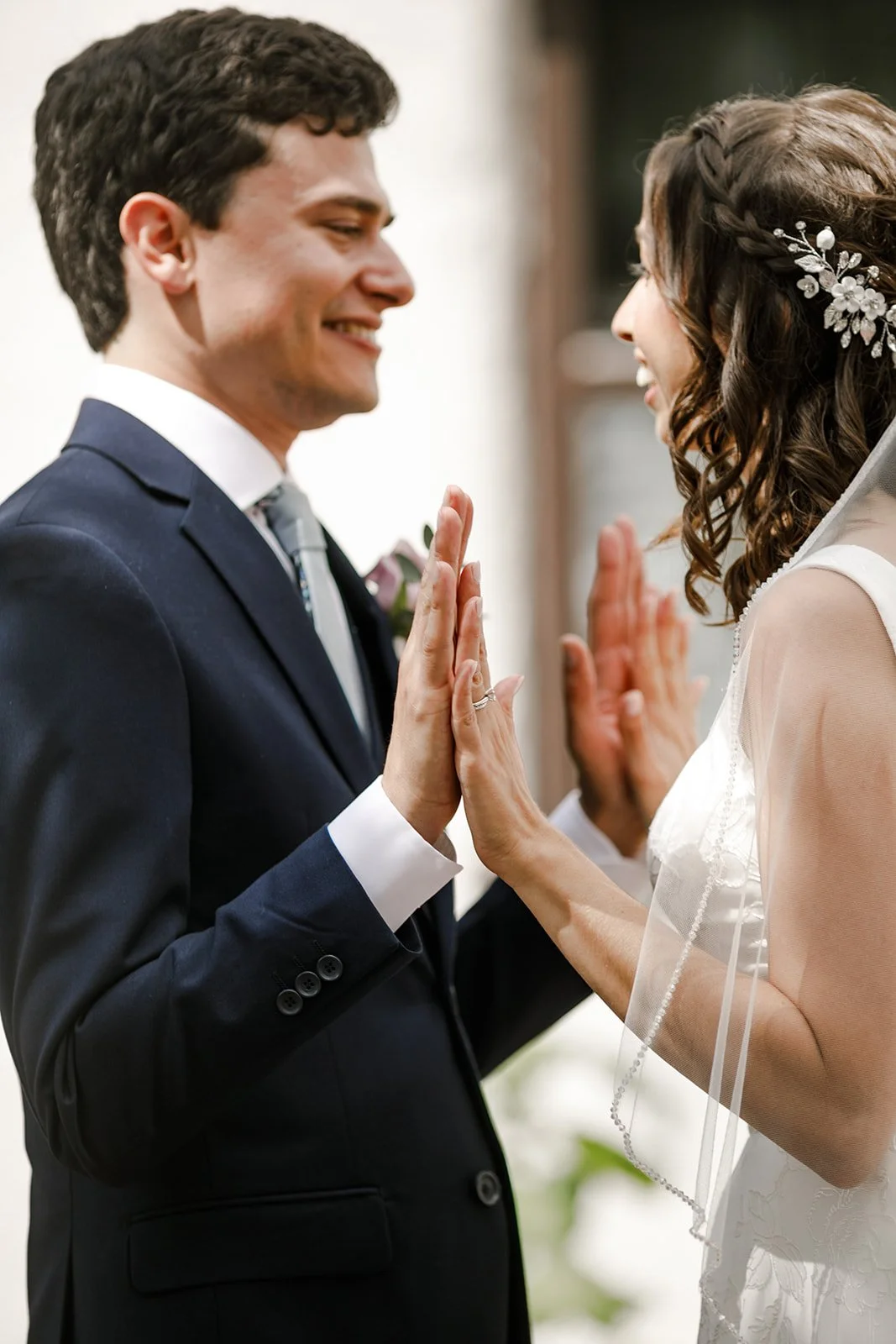 A bride and groom are touching hands and smiling at each other during a wedding ceremony.