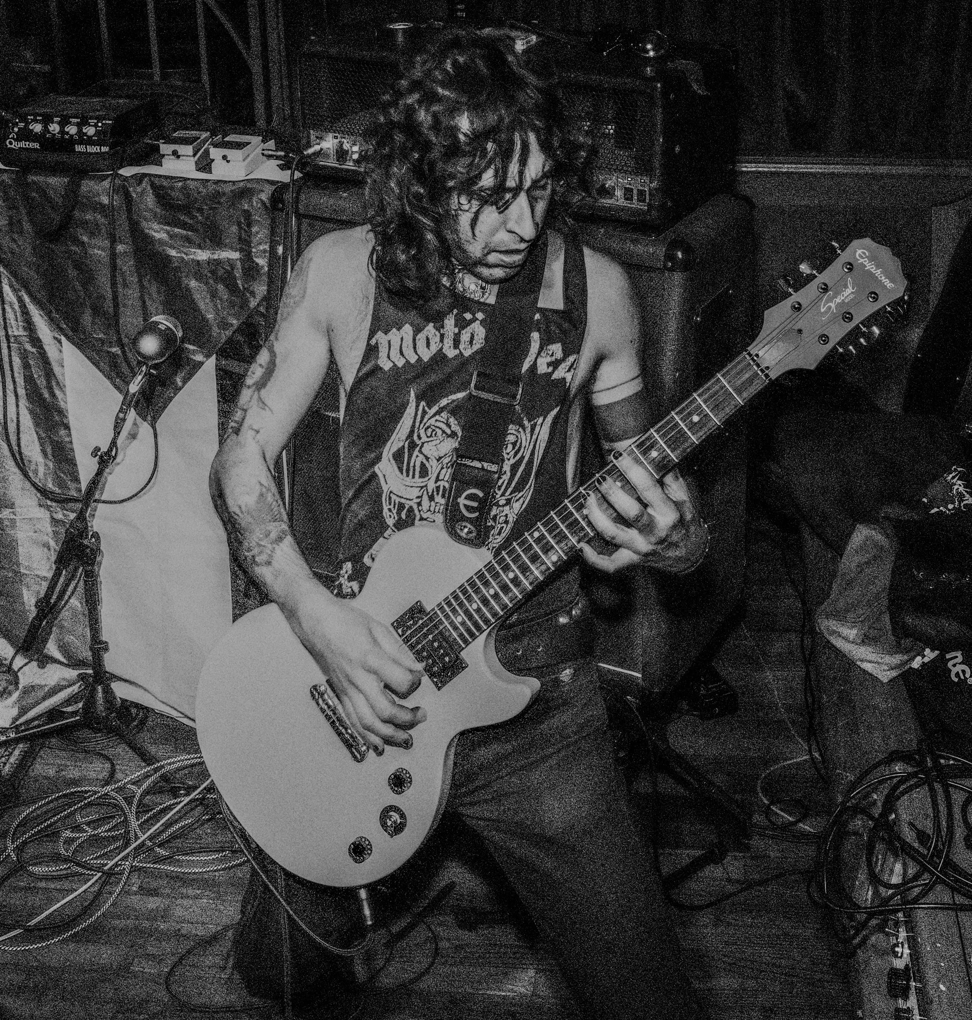 A musician playing an electric guitar during a performance in a black and white photo.
