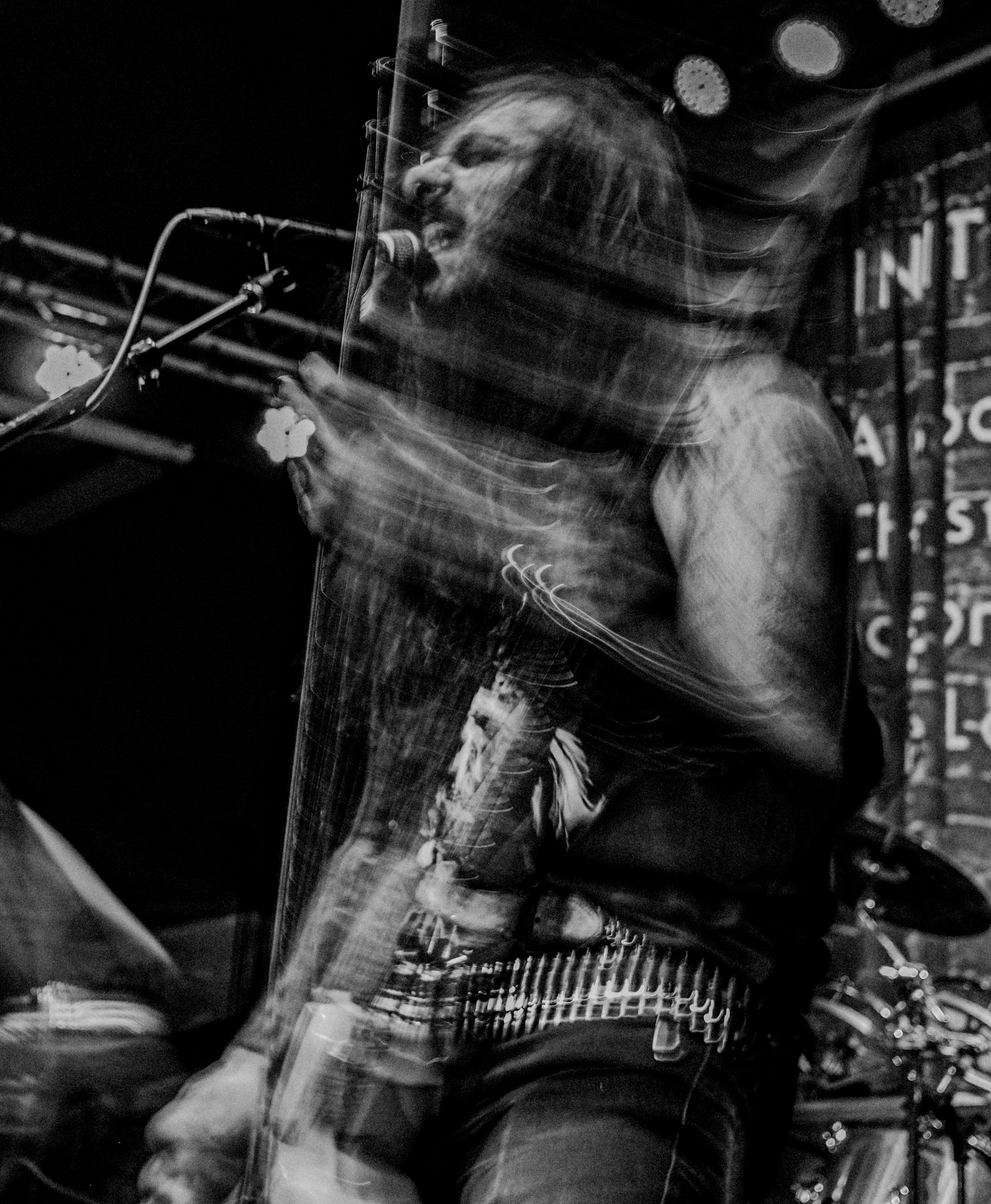 Black and white photo of a singer passionately performing on stage, with motion blur indicating energetic movement.
