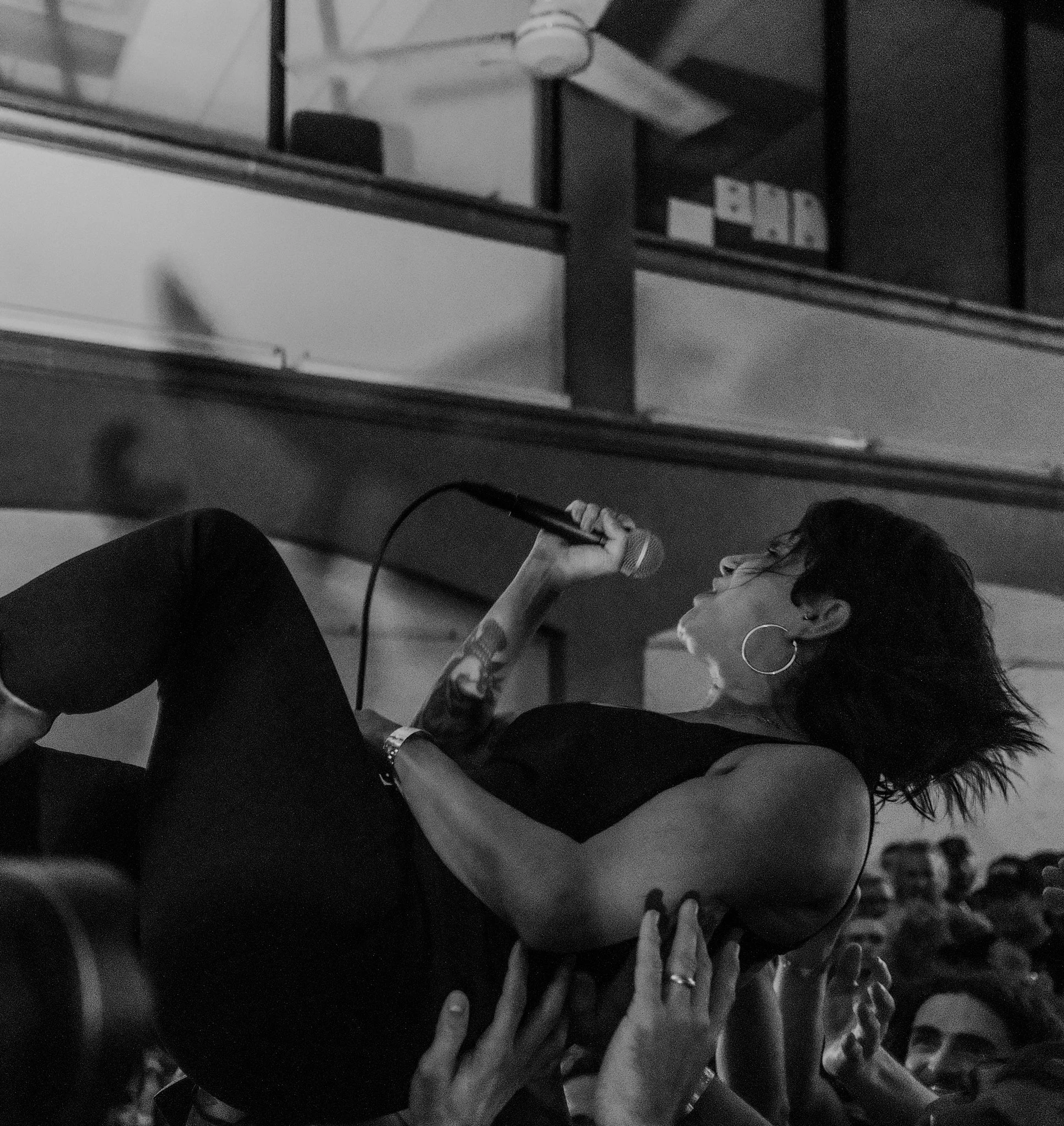 A woman holding a microphone is crowd surfing at a concert.