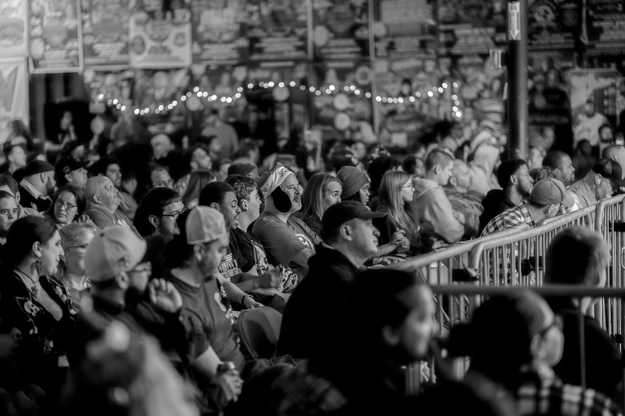 A black and white photo of a large audience sitting in a venue, attentively watching a performance or event.