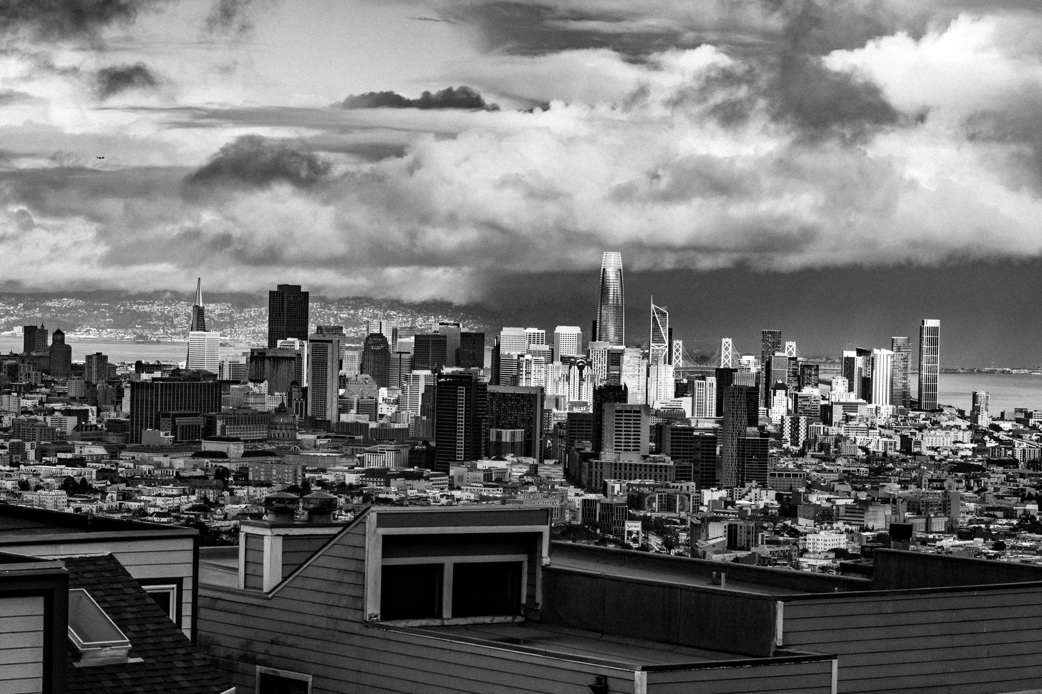 Black and white photo of San Francisco skyline with tall buildings, including the Salesforce Tower, and cloudy sky.