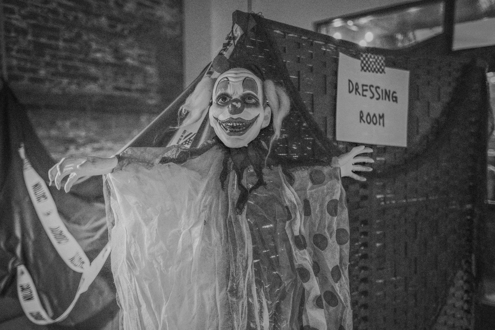 A clown decoration with a smiling face, painted makeup, and wild curly hair, standing in front of a sign that says 'Dressing Room'.