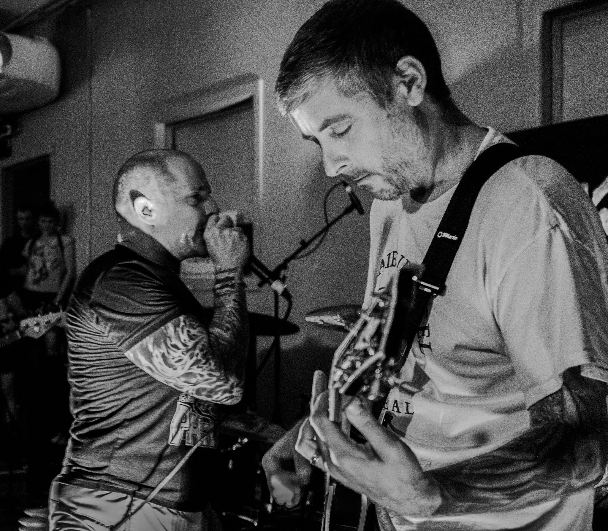 Black and white photo of a band performing live with a singer and a guitarist.
