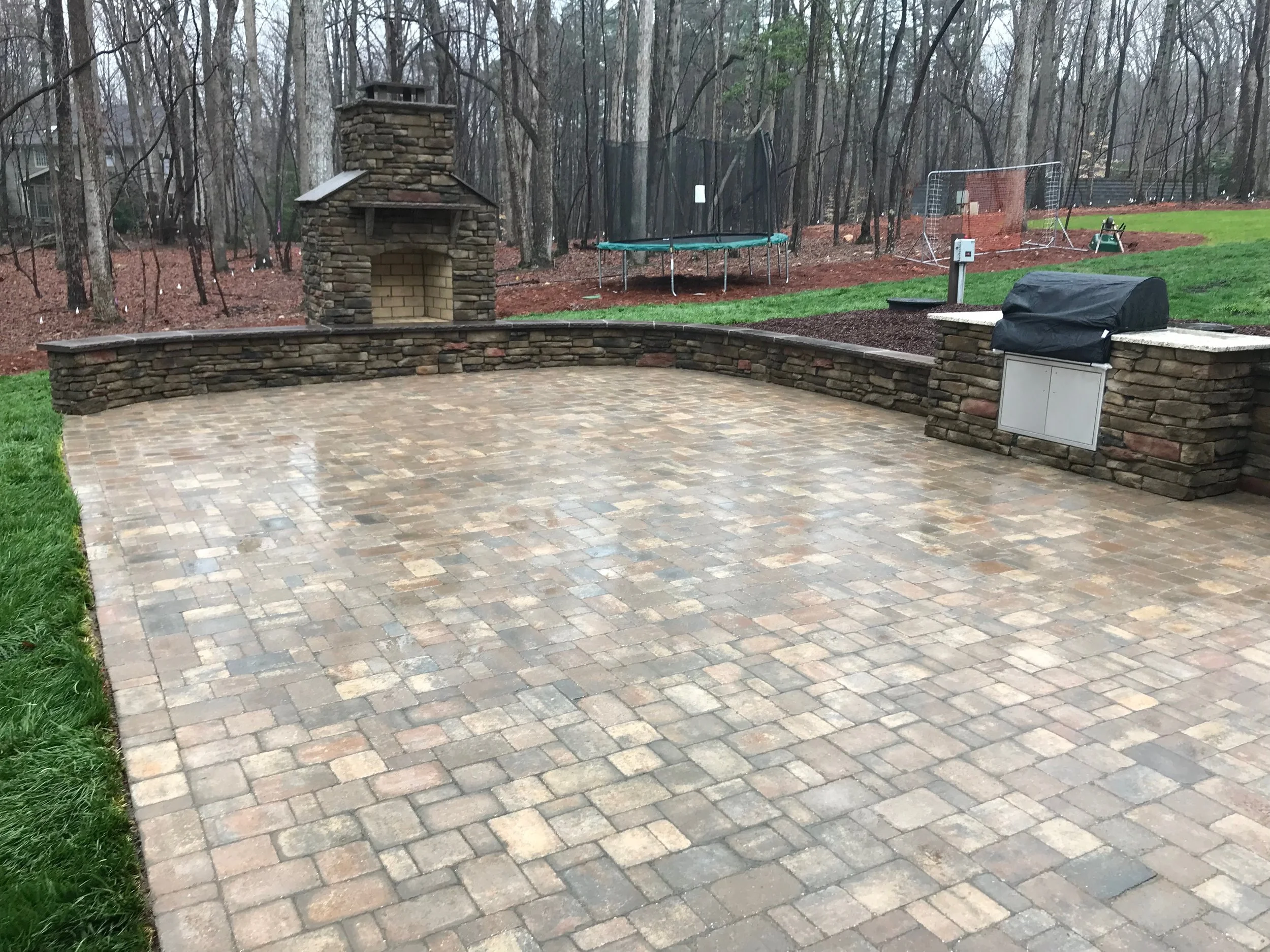 spacious paver patio and outdoor fireplace with large seat wall