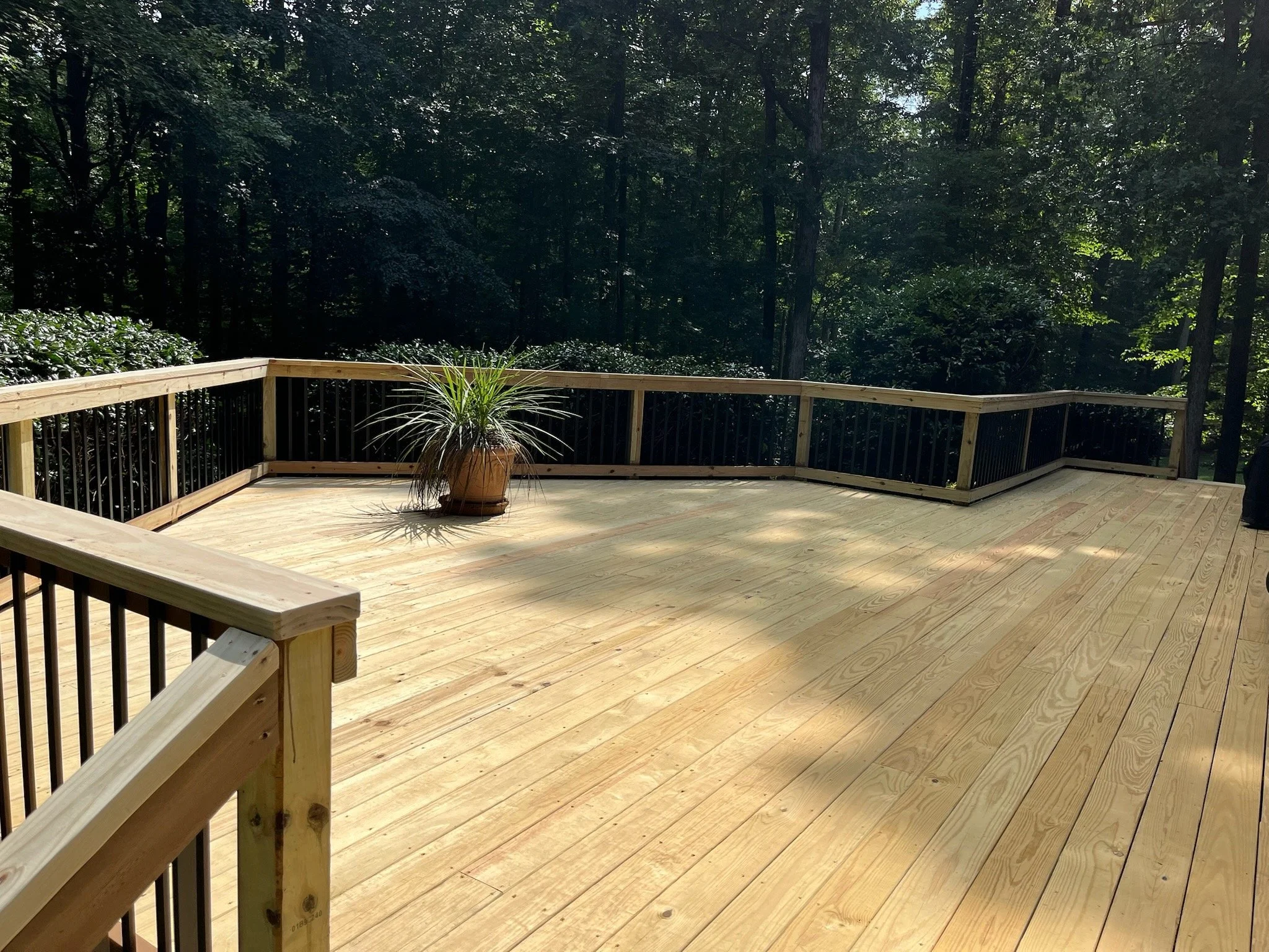 Custom wooden deck surrounded by a black metal railing.