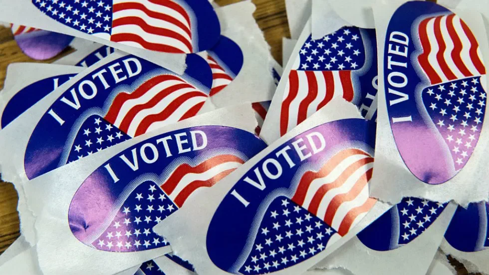 Several 'I Voted' stickers with the American flag design are scattered on a surface.
