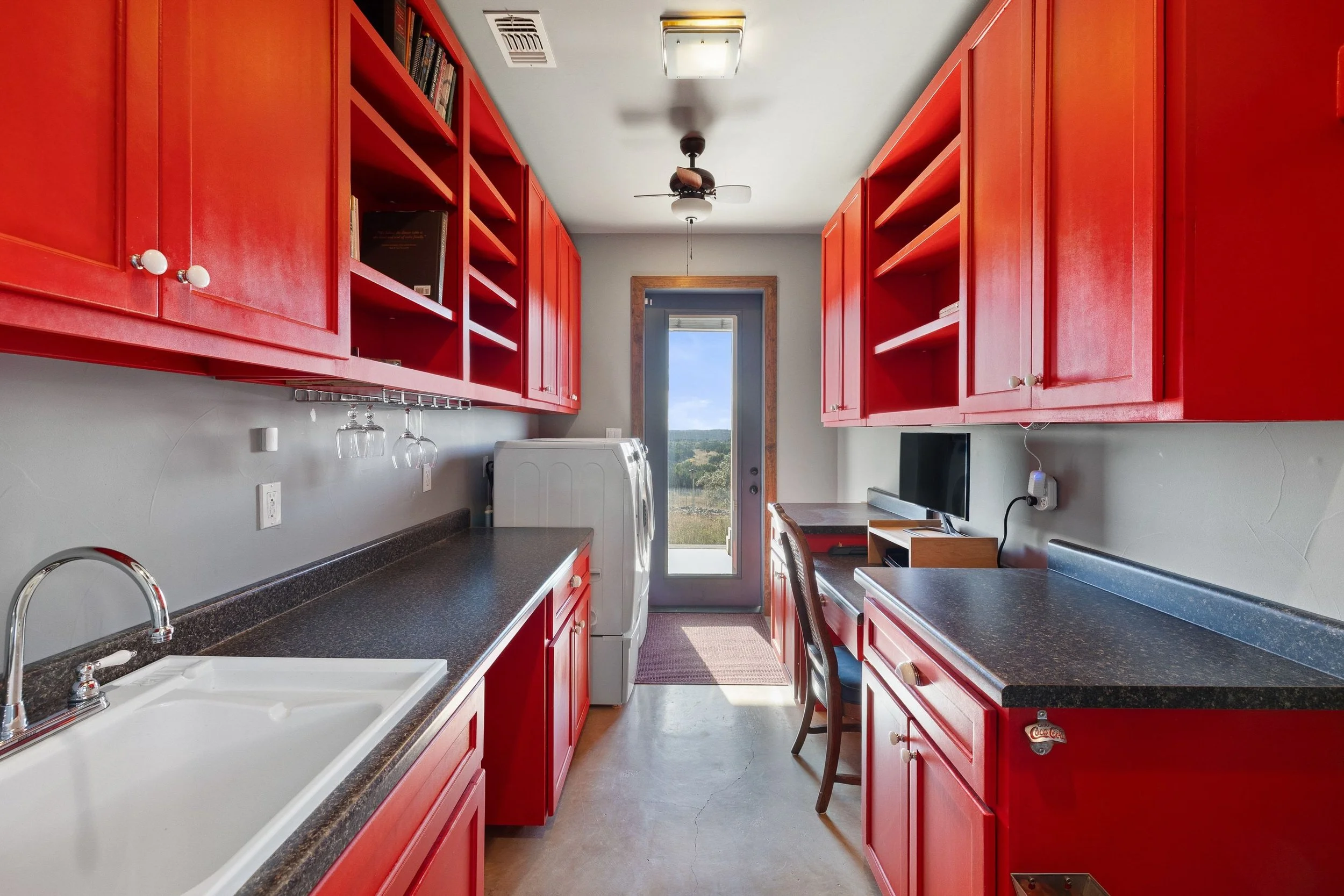 Red laundry room with black countertops, utility sink and washer and dryer.