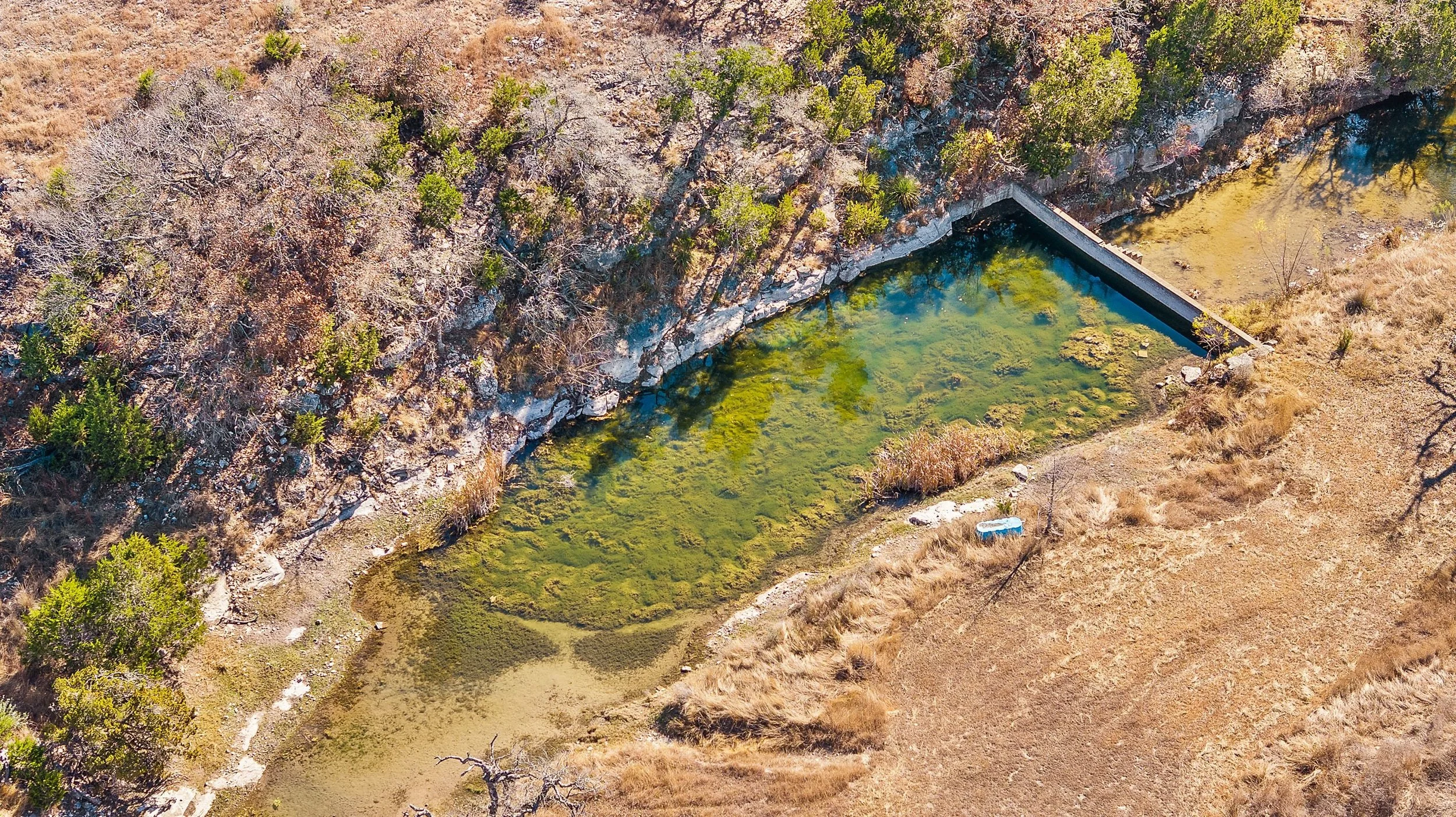 An aerial view of a small pond with clear water.