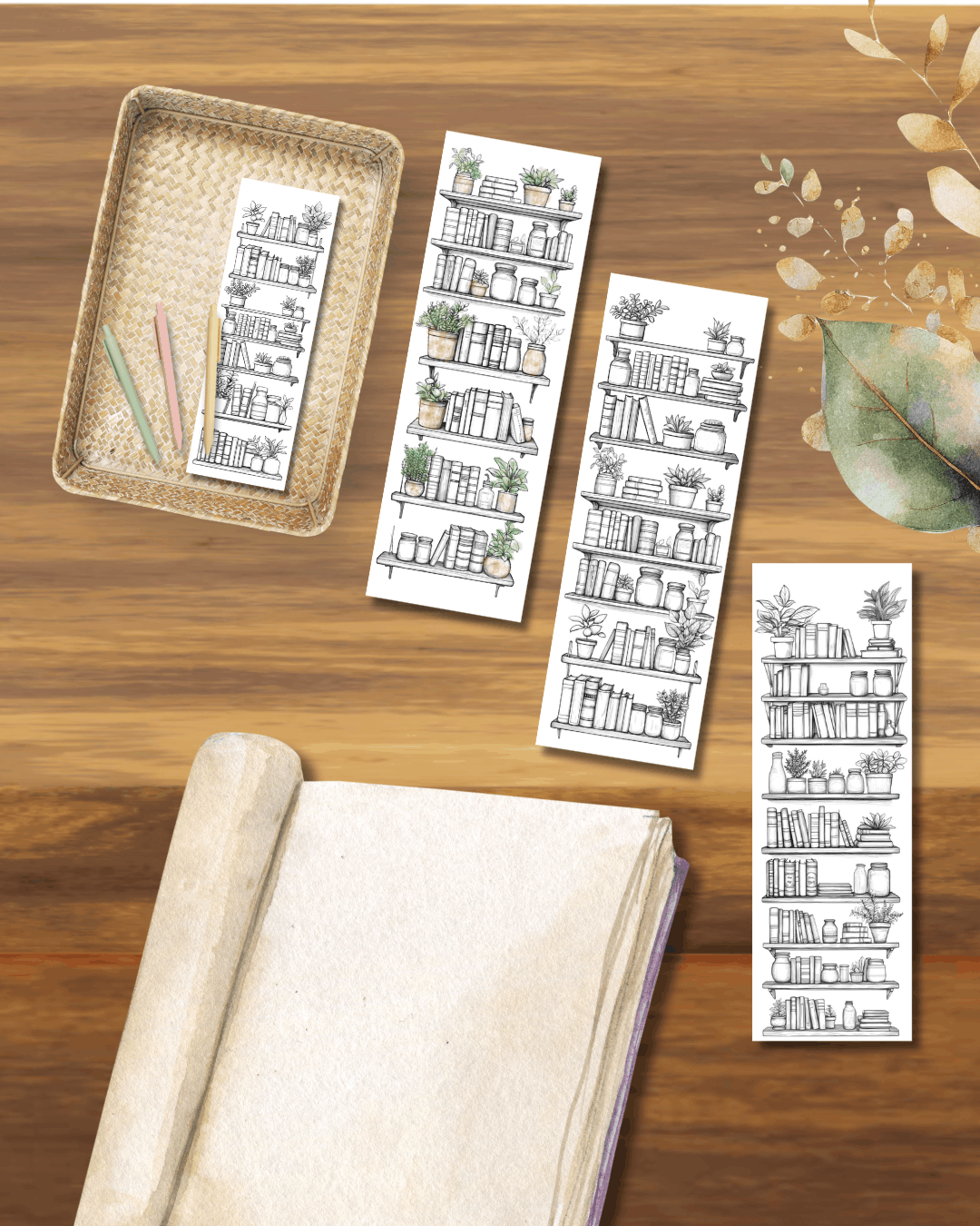 A wooden table with a notebook, a woven tray with colored pens, and four scrolls of black and white illustrations of bookshelves with plants.