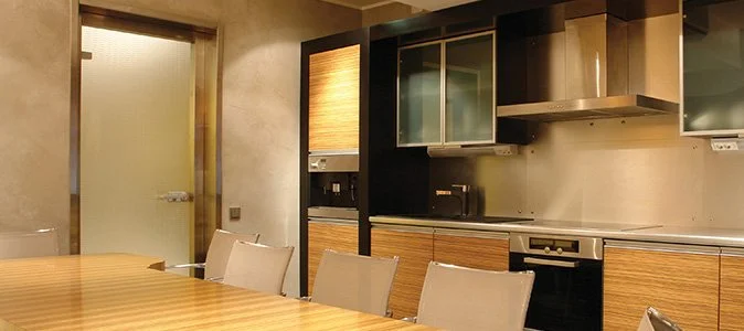 Modern kitchen with wooden cabinets, a dining table with beige chairs, and stainless steel appliances.