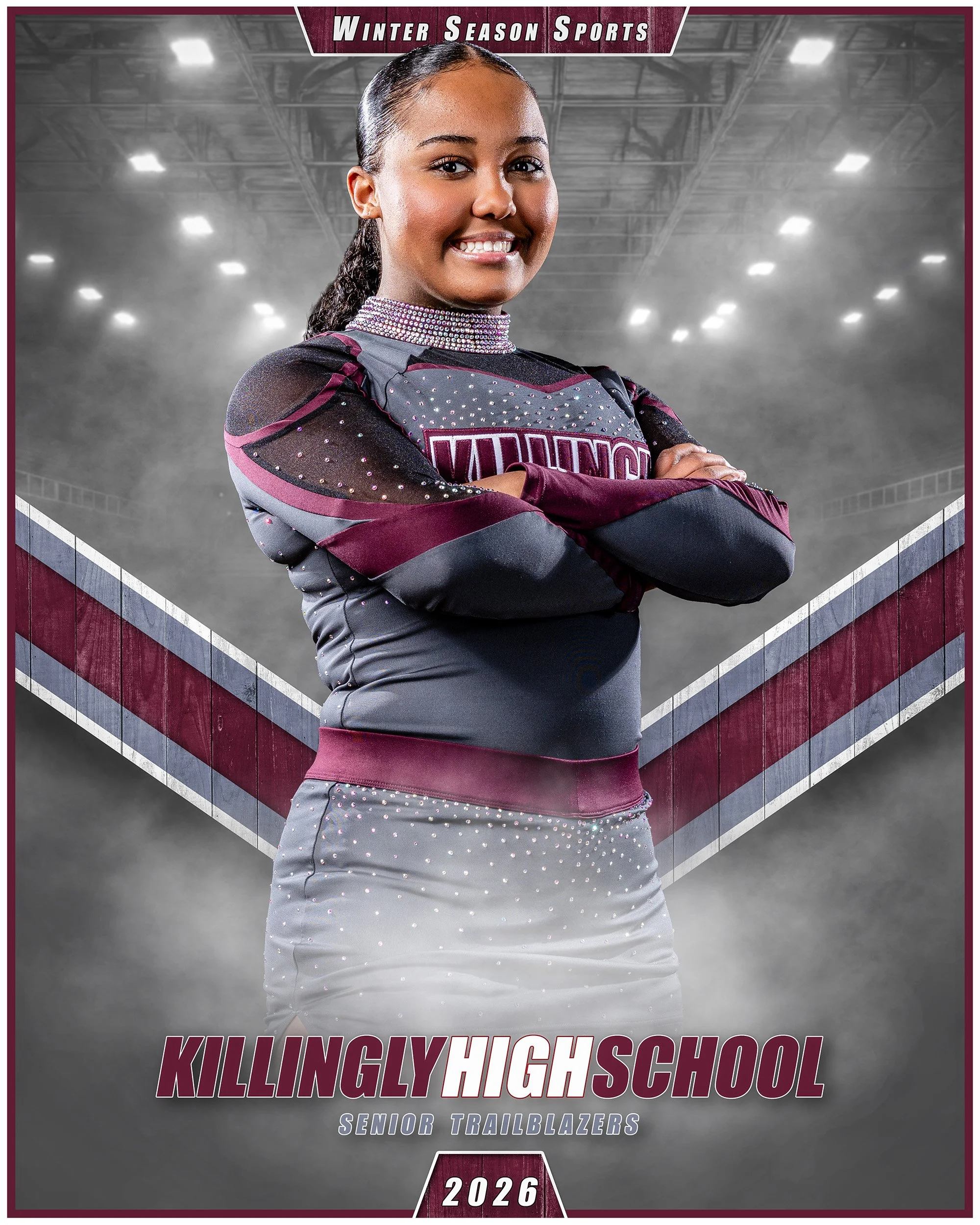 A young female cheerleader in a maroon and gray cheerleading uniform with rhinestones and the word 'VIKINGS' on it, standing with arms crossed and smiling, in a sports arena with bright lights and a smoky backdrop, promoting the Killingly High School