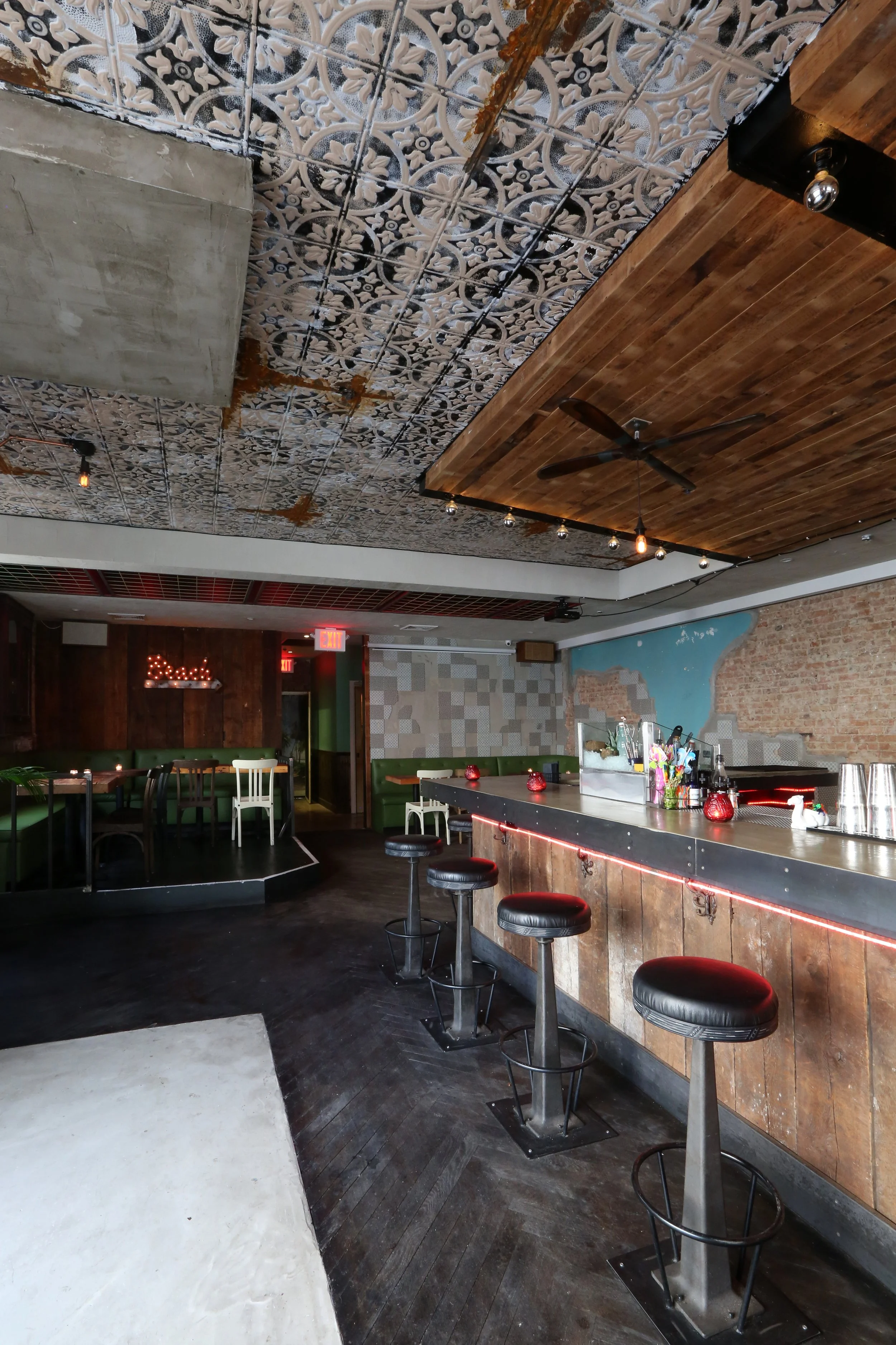 rustic bar with black leather barstools, herringbone floors, and rugged accent walls
