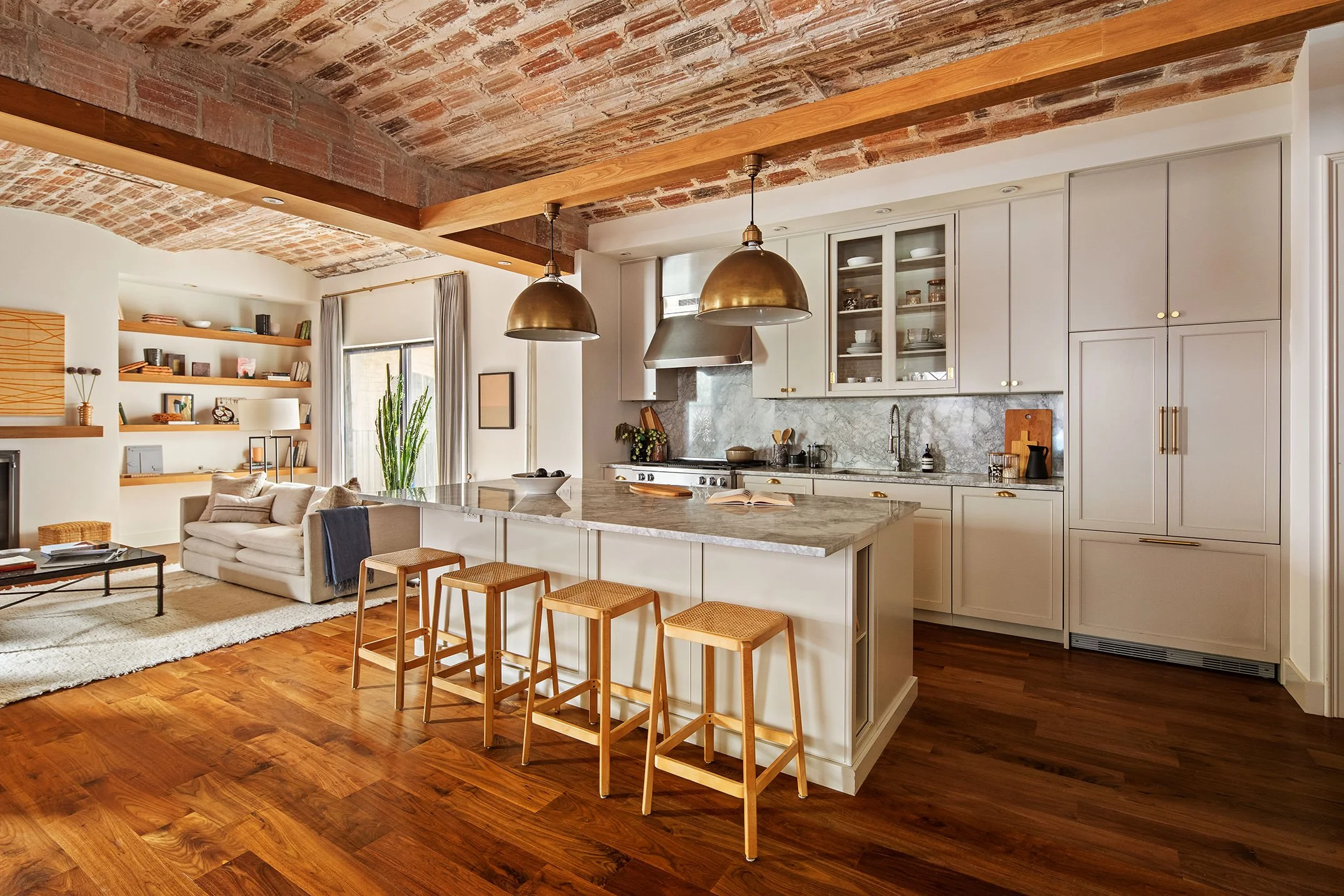  kitchen as seen from behind barstools arranged at a white marble island 