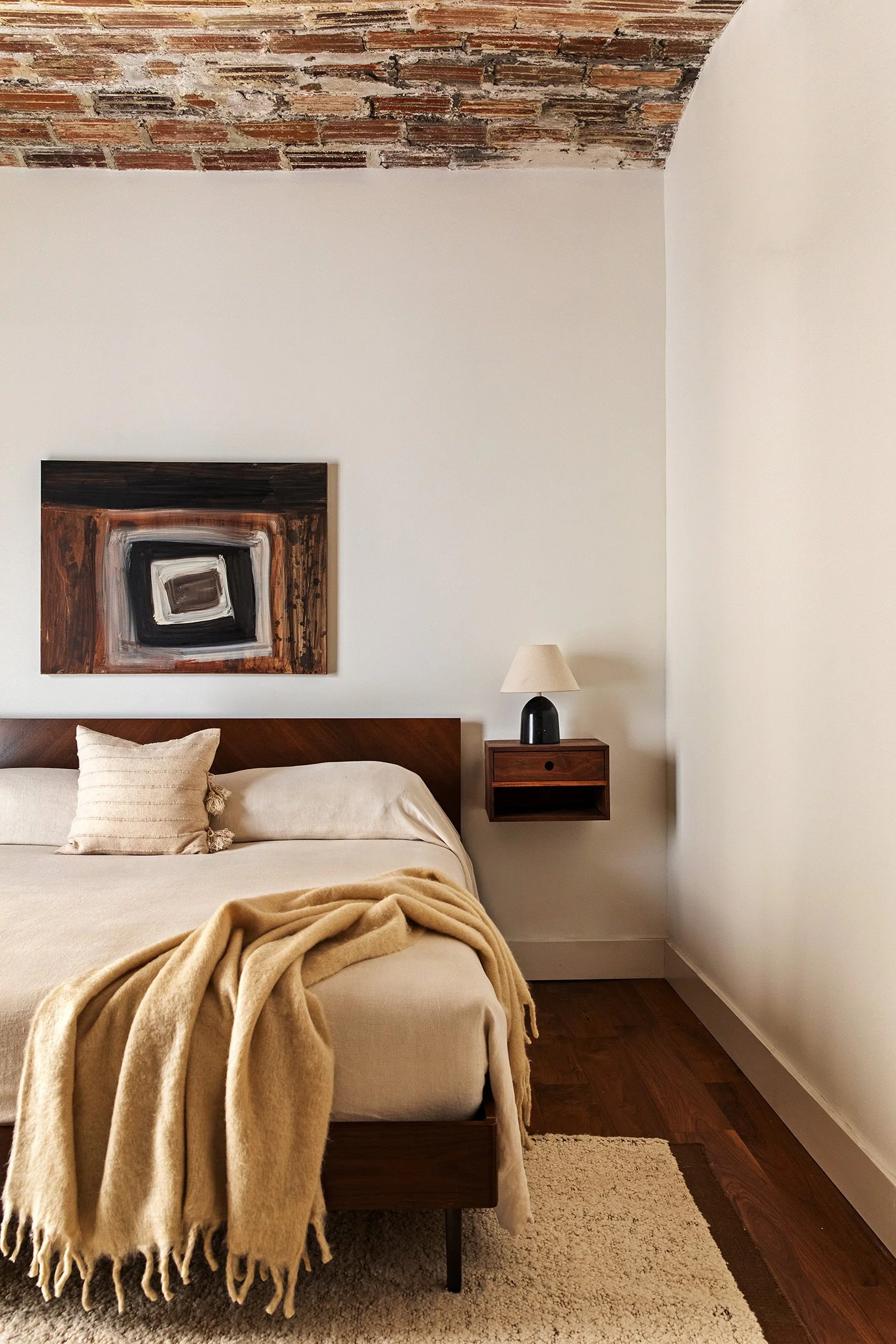 bed with wooden bed frame, floating wooden nightstand, and neutral luxury bedding