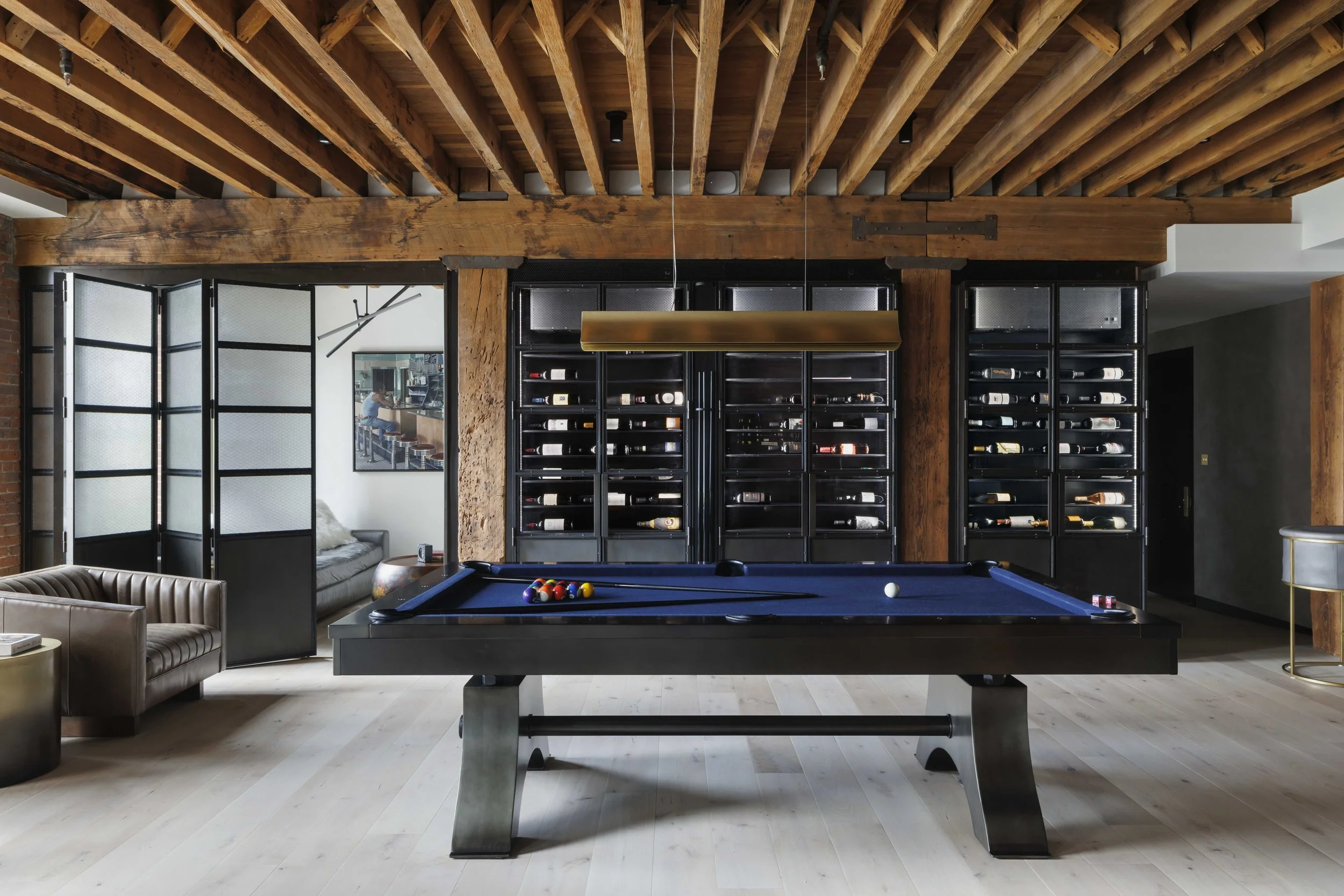  game room with blue pool table and shelves filled with a wine collection 