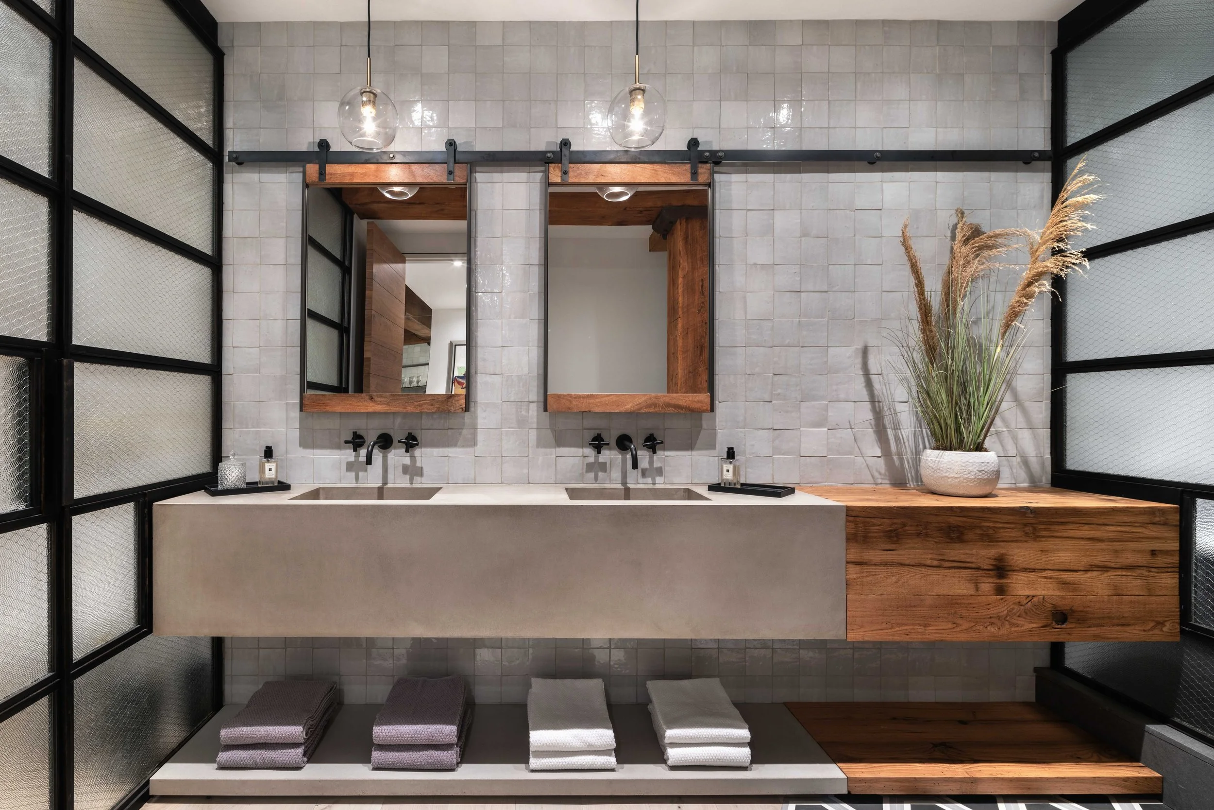  sleek brutalist bathroom sinks that are partially concrete with a wooden accent and glass neighboring partition walls 