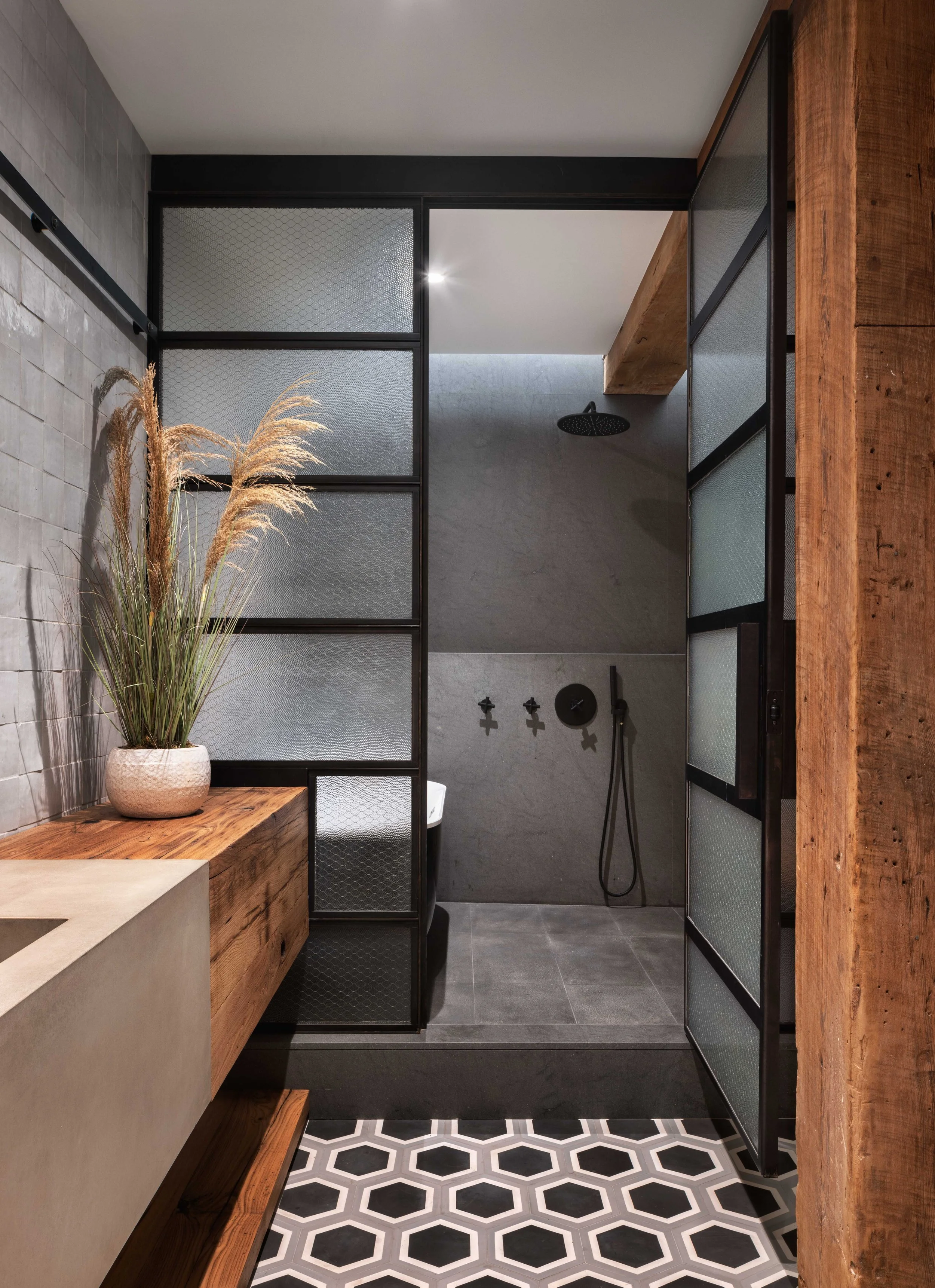  sleek grey stone shower with paneled window partition and black and white tiled flooring 