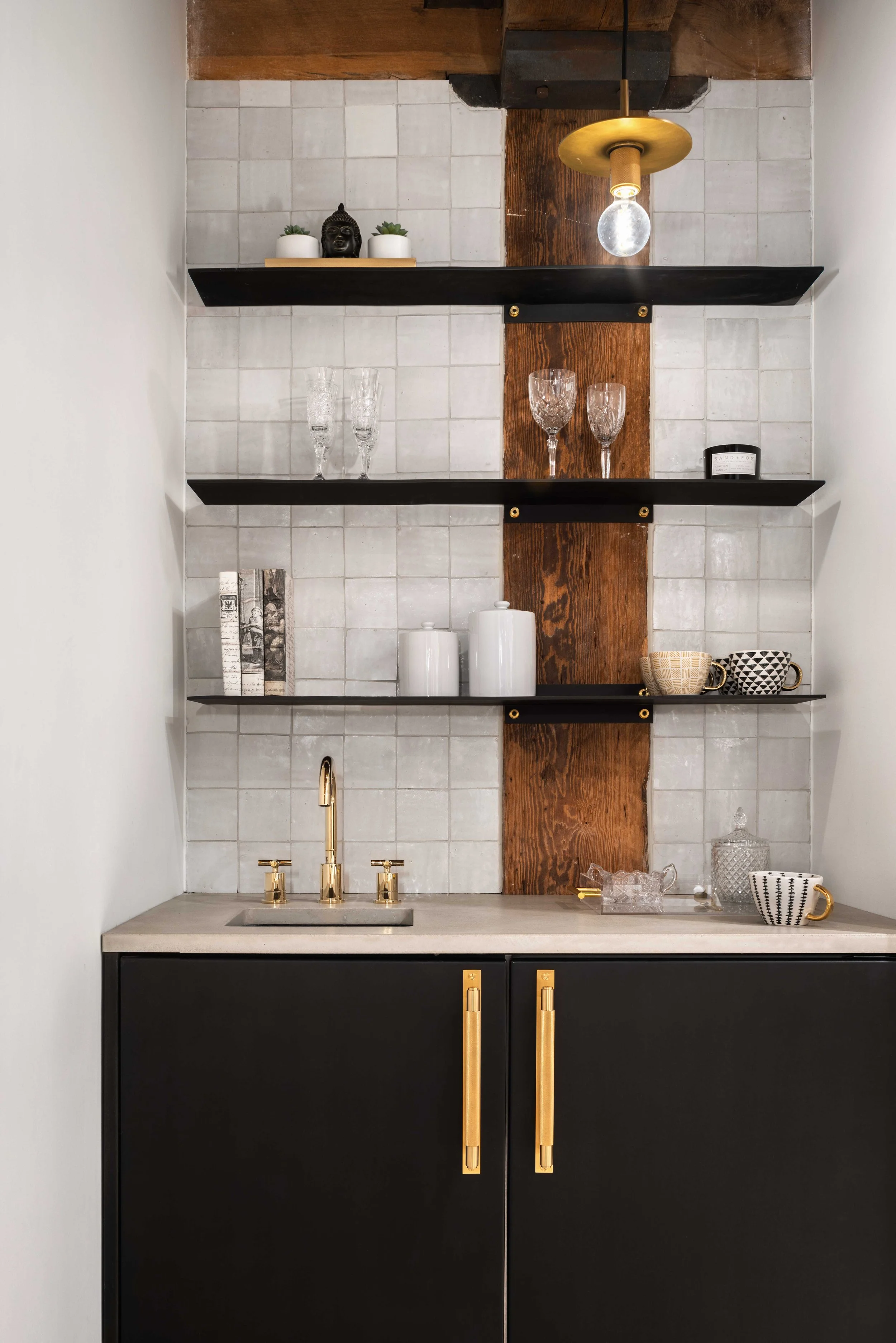  modern black floating shelves with white tile and wood beam backsplash with black cabinetry below 