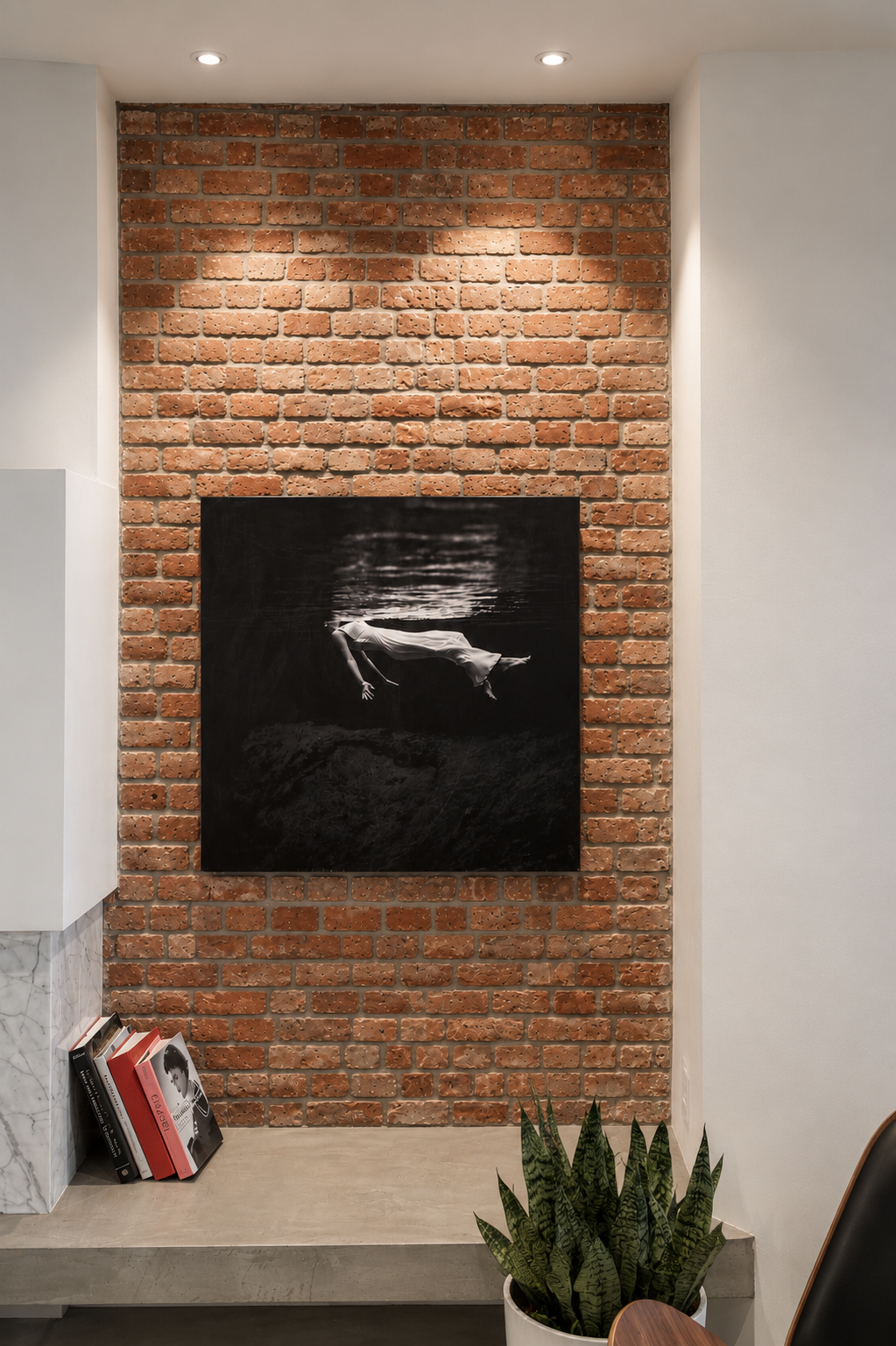  reading nook with brick accent wall and black artwork with book stack and plant accent 