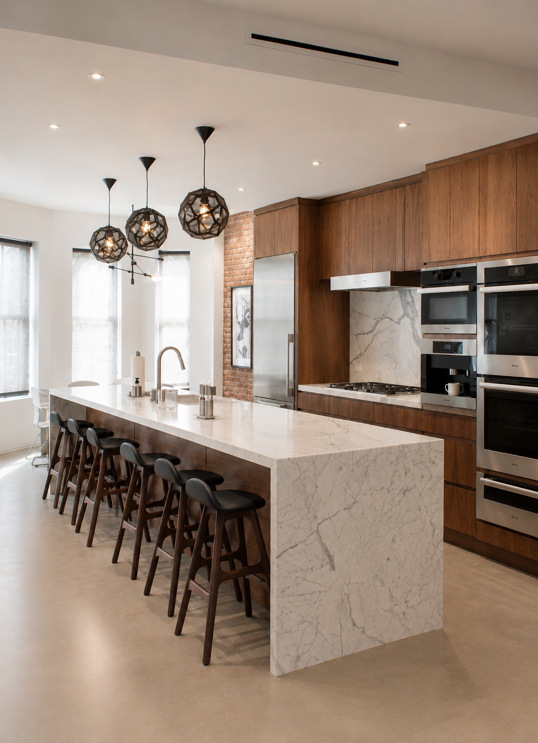  angled view of modern kitchen space with large marble island and cool toned appliances and cabinetry 
