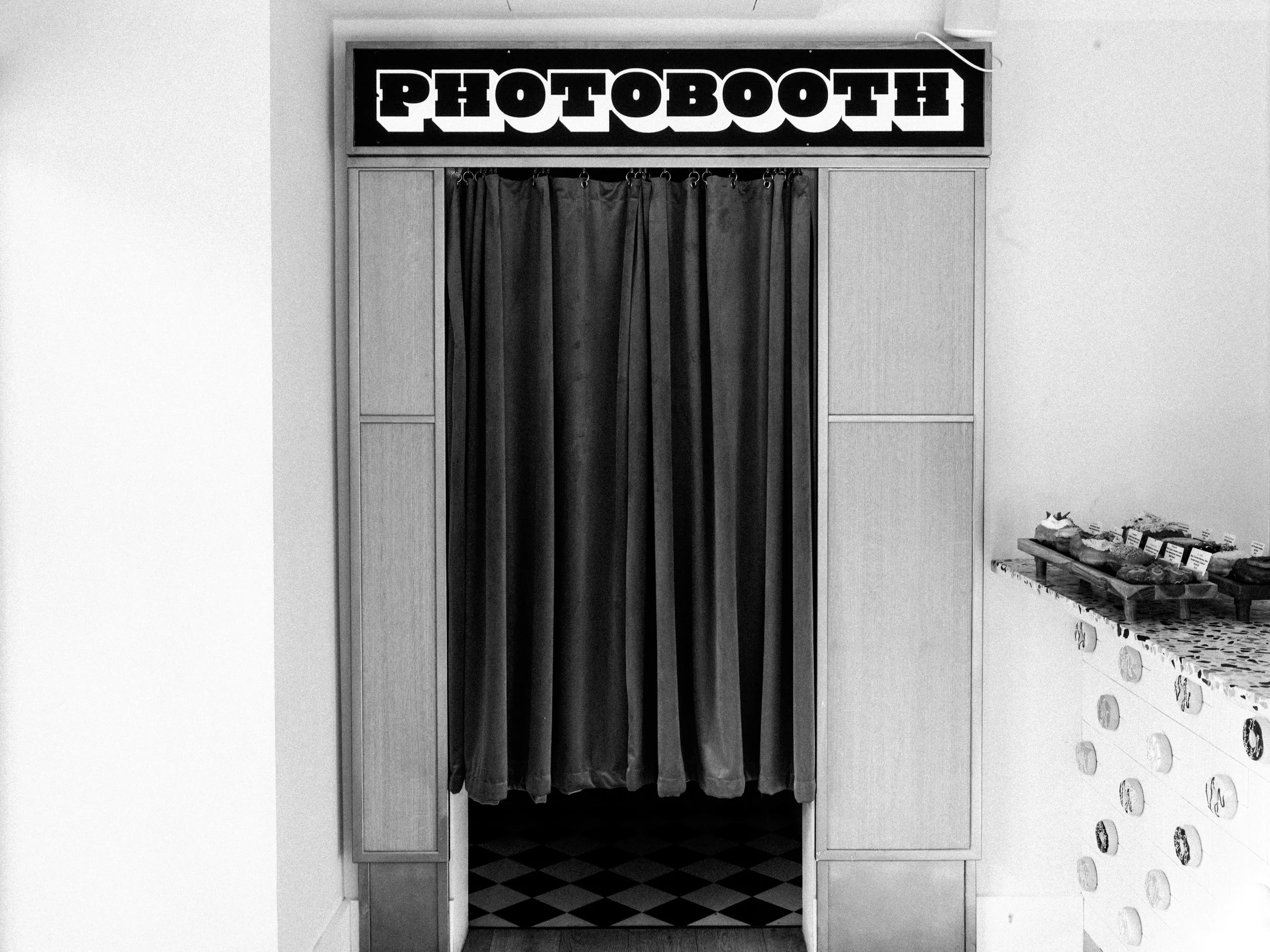  black and white image of exterior of photobooth with velvet curtain 