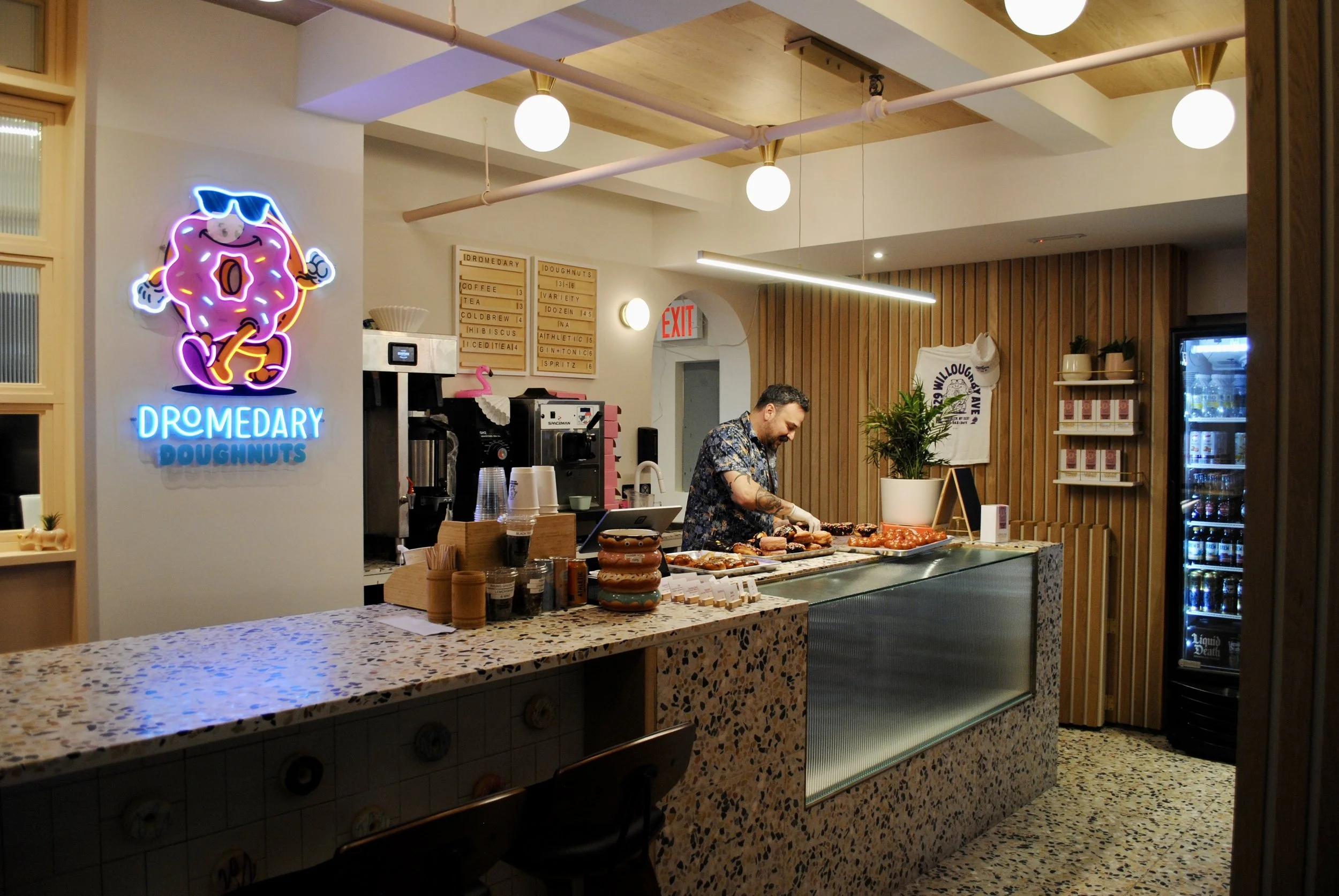  counter for dromedary doughnut with neon sign and speckled stone countertop 