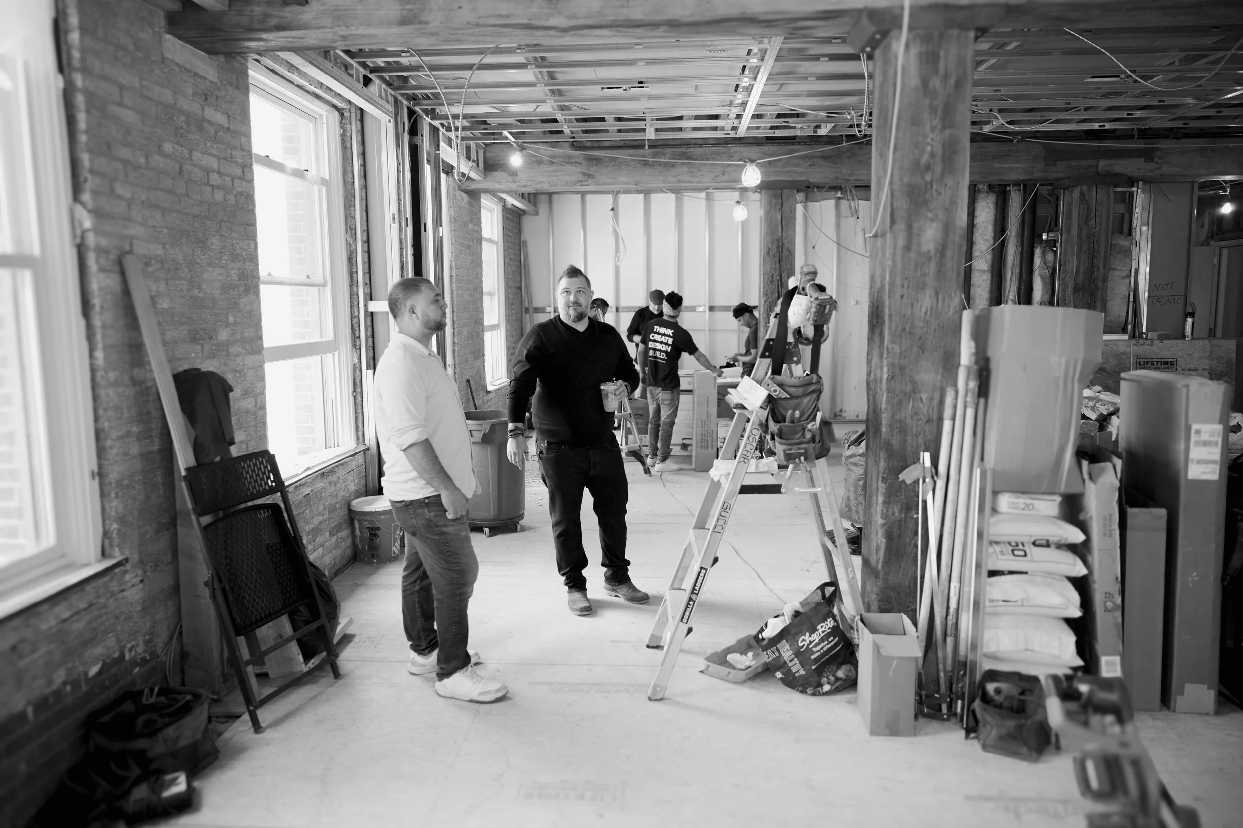 founders of cargo workshop in active construction area looking at exposed beams