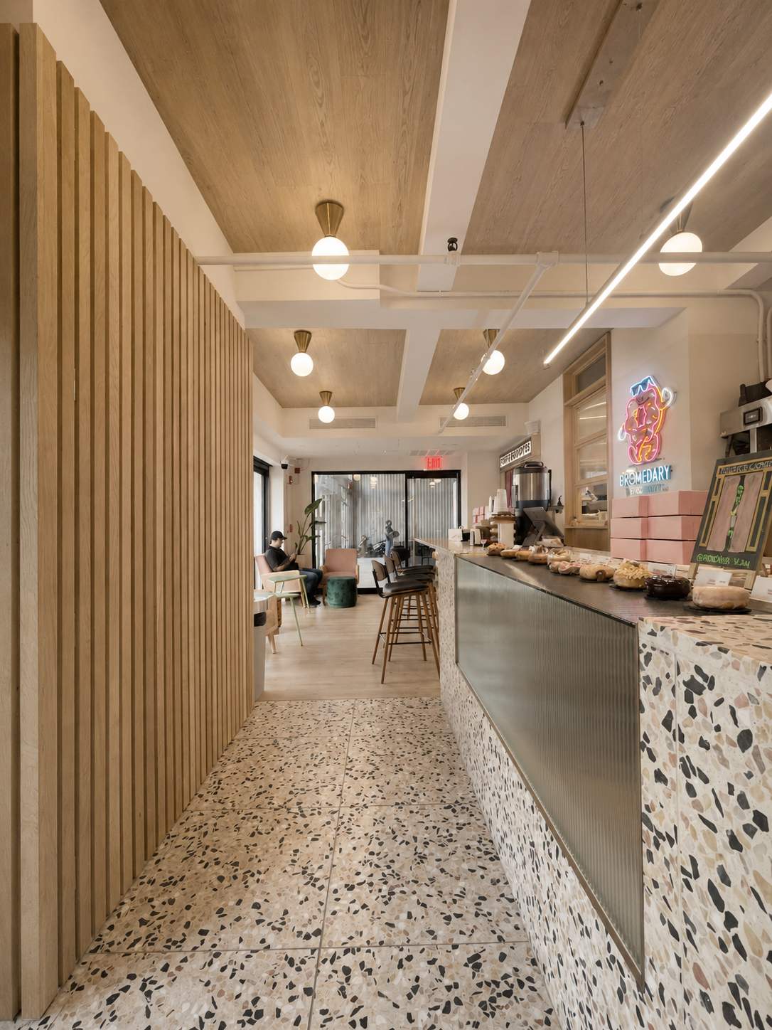 view of barstools from hallway with speckled tile accents and man reading menu in the corner in a pink chair