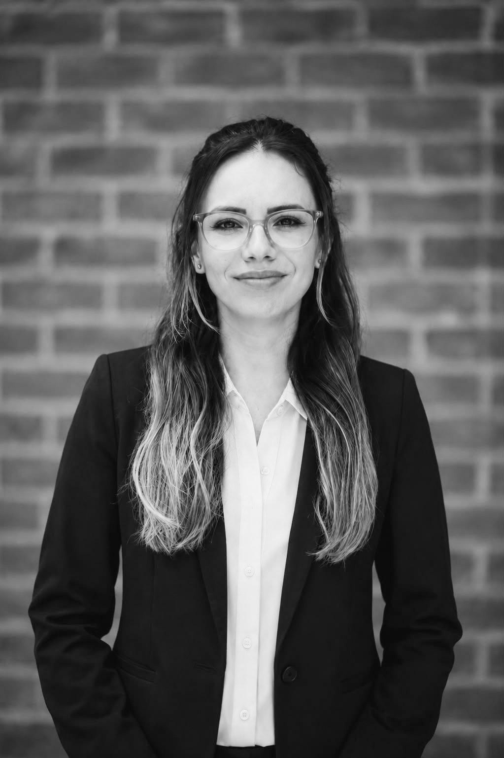 A woman with long gradient hair, glasses, and a black blazer