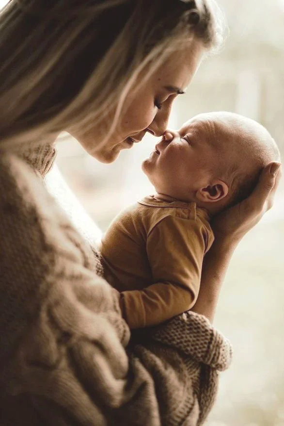 A woman holds a baby close, with their foreheads touching in a loving gesture.