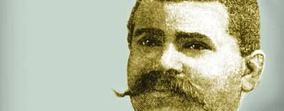 A sepia-toned portrait of a man with a thick mustache and short hair, dressed in vintage clothing.