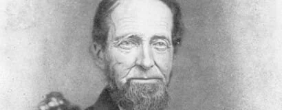 A black-and-white portrait of a man with a beard and mustache, wearing a suit.