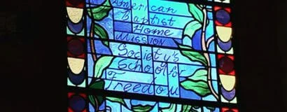 A colorful stained glass window with handwritten notes on paper attached to it.