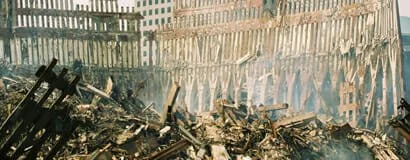 Scene of destruction with charred debris, burnt wood, and smoke.