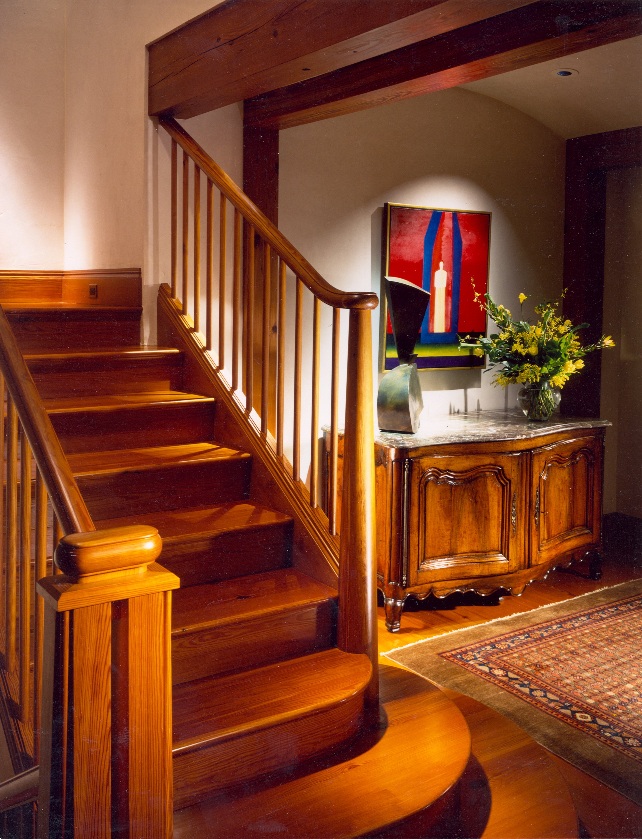 Residential interior by Winfield Studio with custom wood staircase, marble-topped sideboard, and curated artwork.