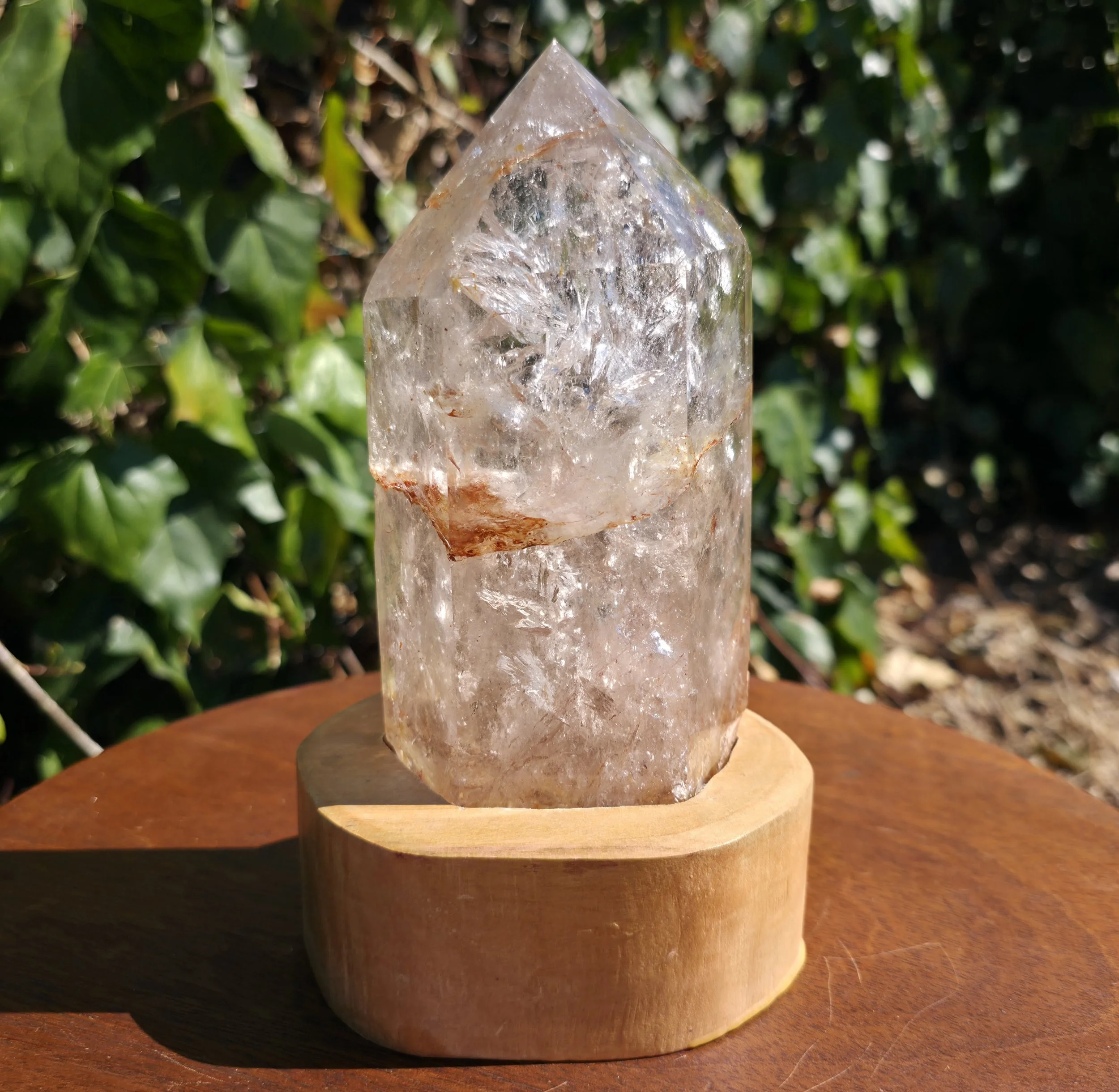 Clear Quartz Point w/Hematite Inclusions on Wood Stand