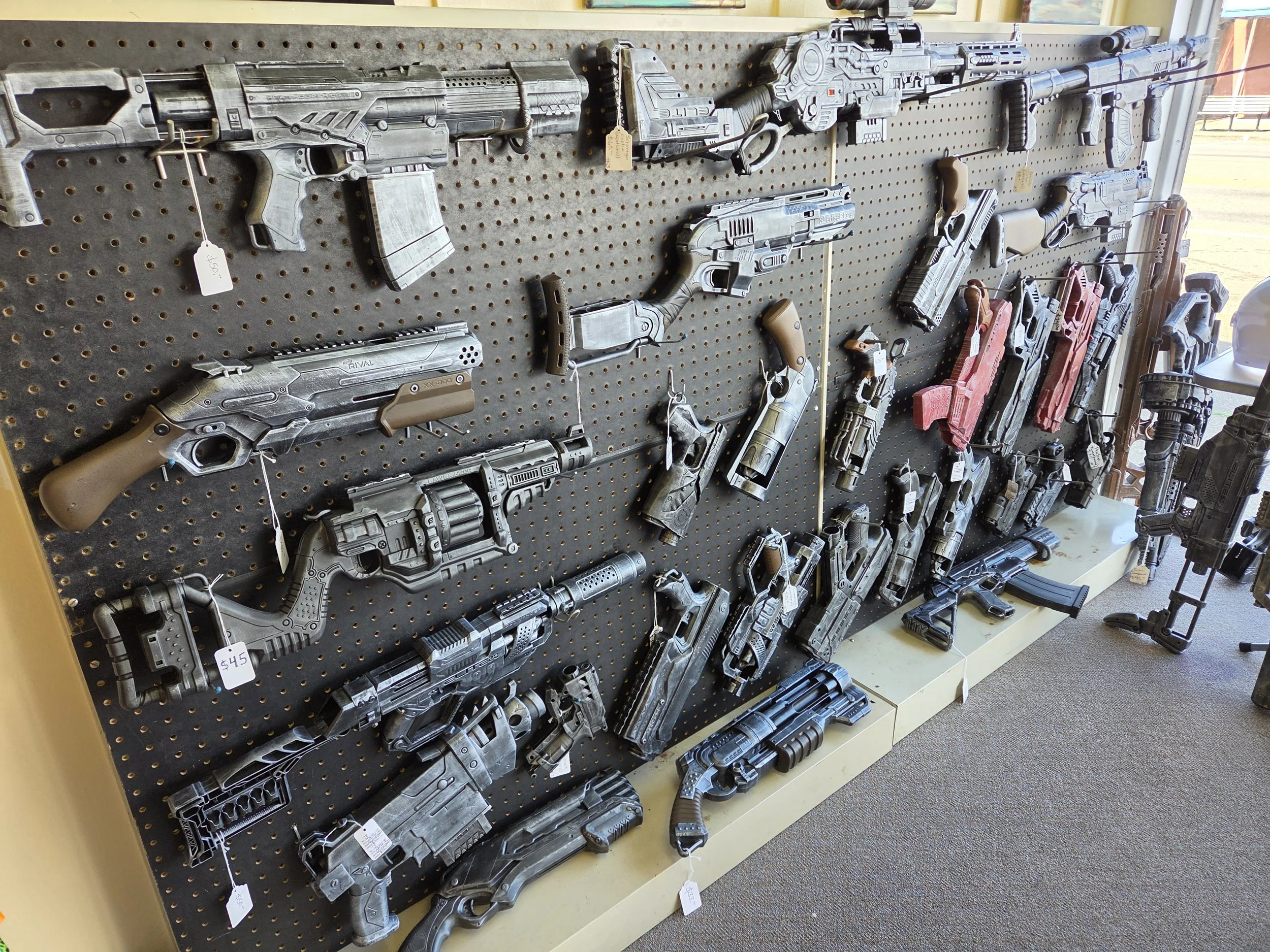 Peg boards and tables displaying a variety of custom painted and colorful original Nerf guns and equipment