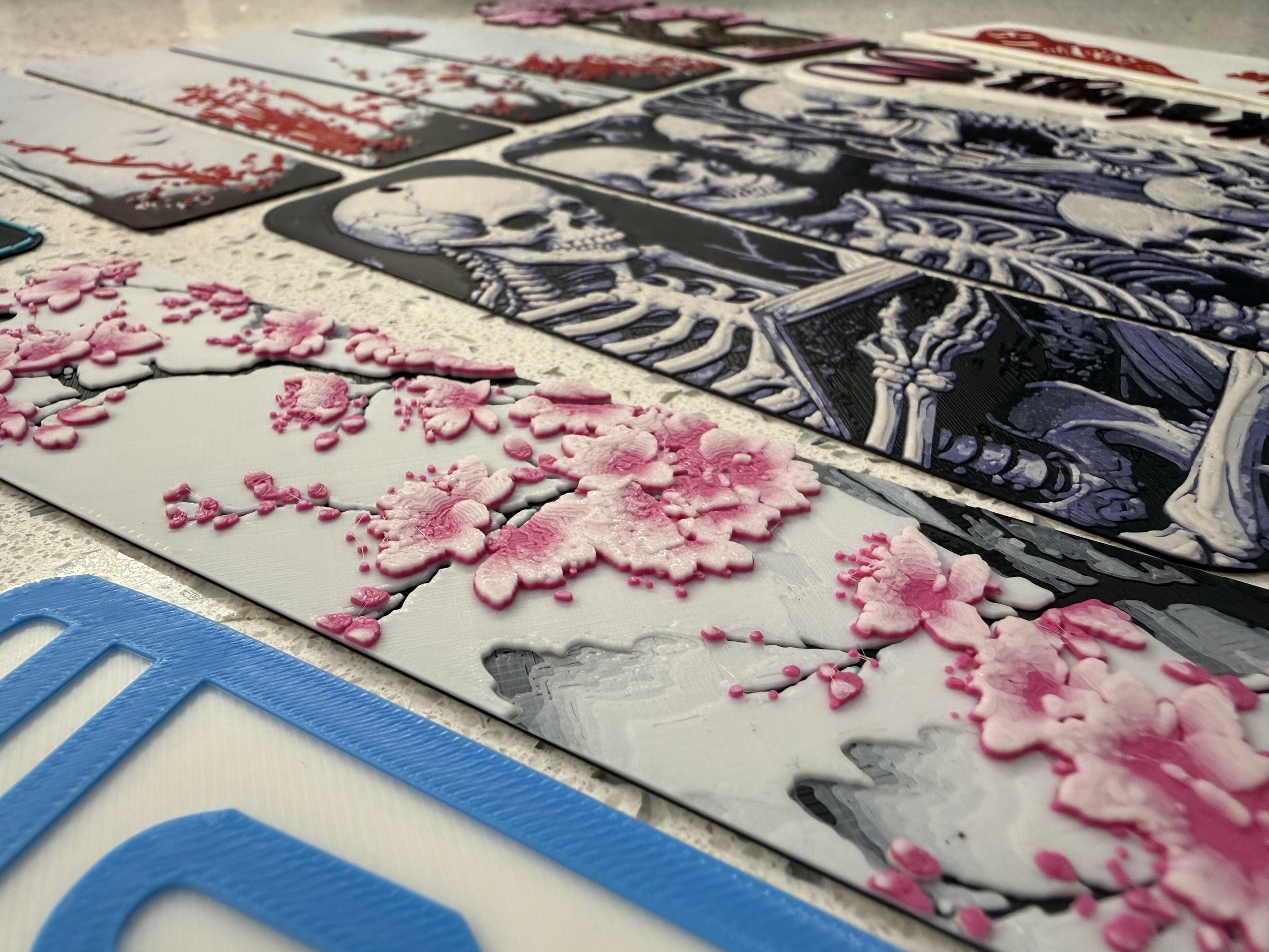 Close-up of 3D printed bookmarks with various designs, including cherry blossoms, skeletons, and more.