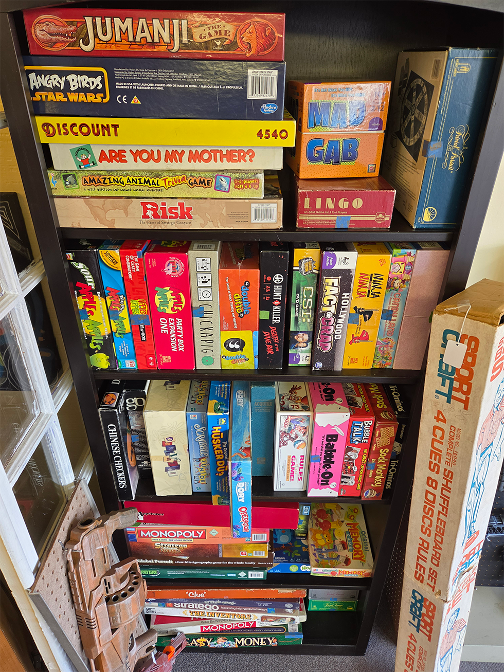 A shelf displaying various second hand boardgames