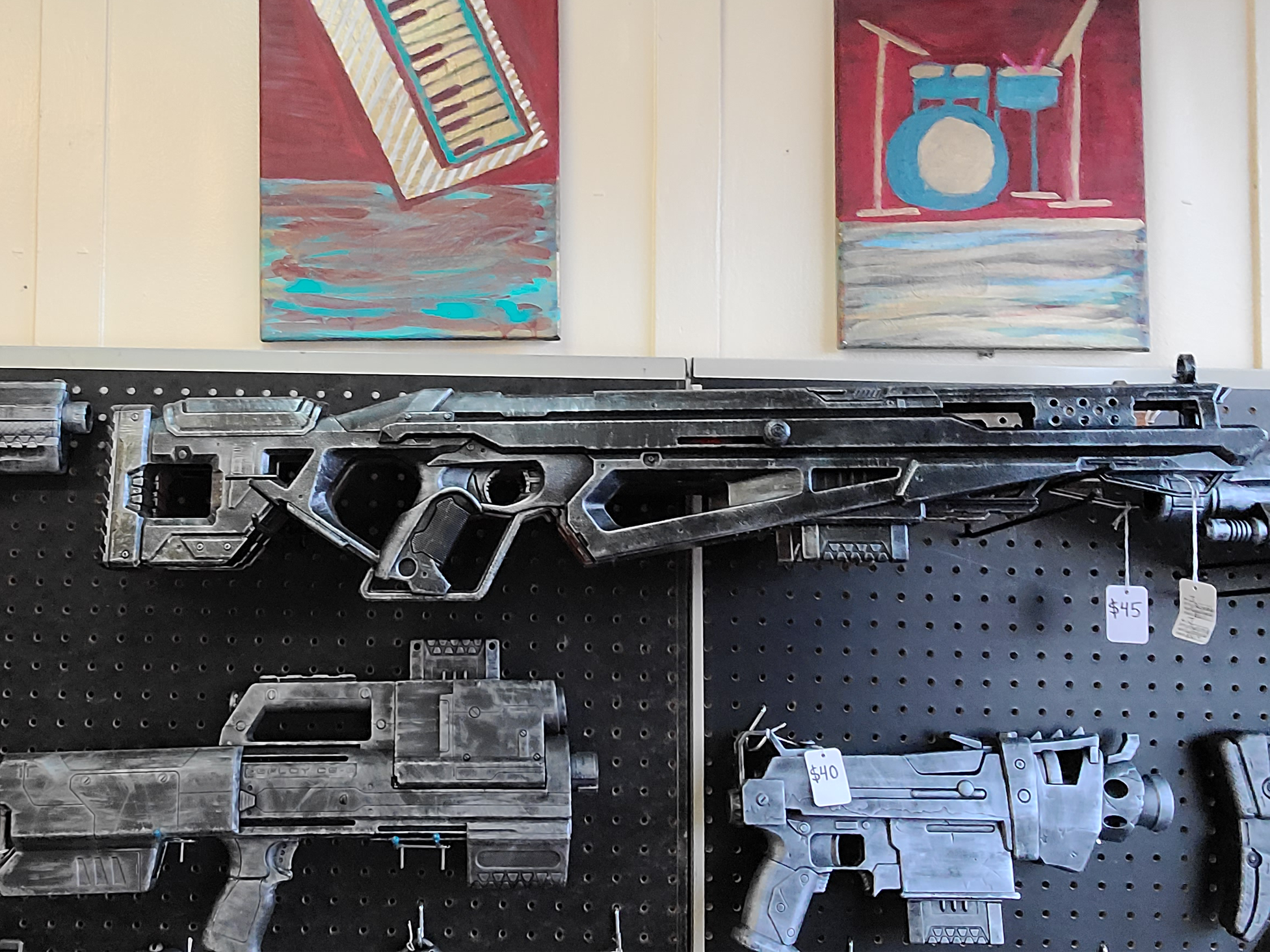 A display of custom painted toy Nerf guns with a black and gray color scheme hanging on a pegboard wall.