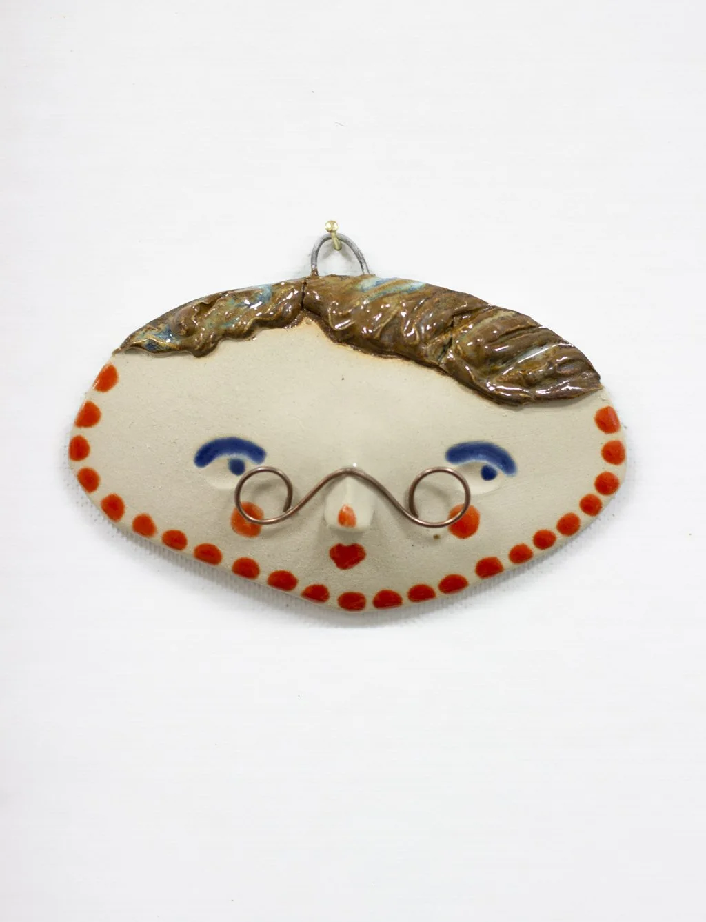 Käsintehty keramiikkanaama, jossa kupariset silmälasit