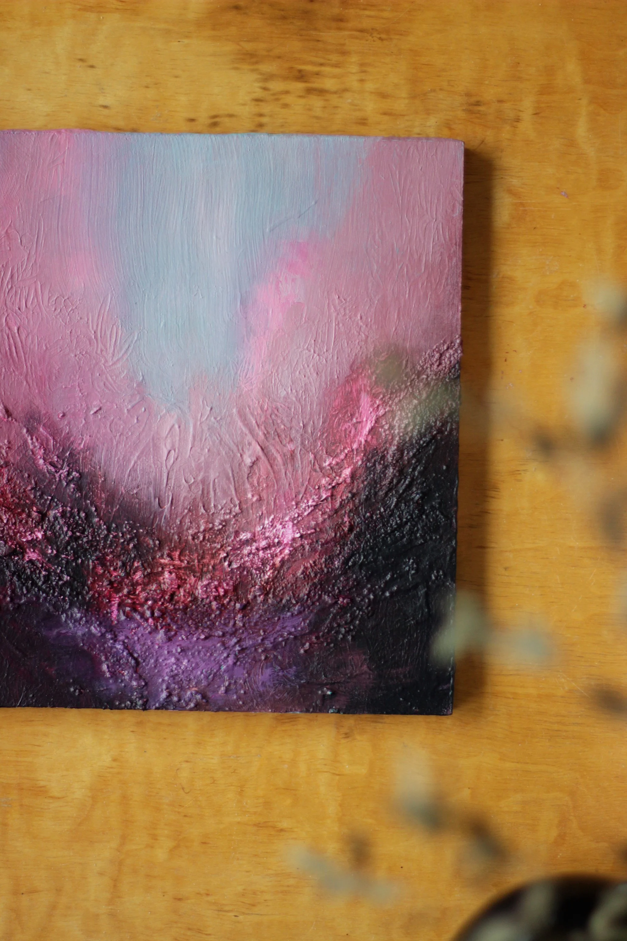 Abstrakti taideteos, jossa on vaaleanpunaisia, mustia ja lilaisia sävyjä, maalattu paksulla tekstuurilla.