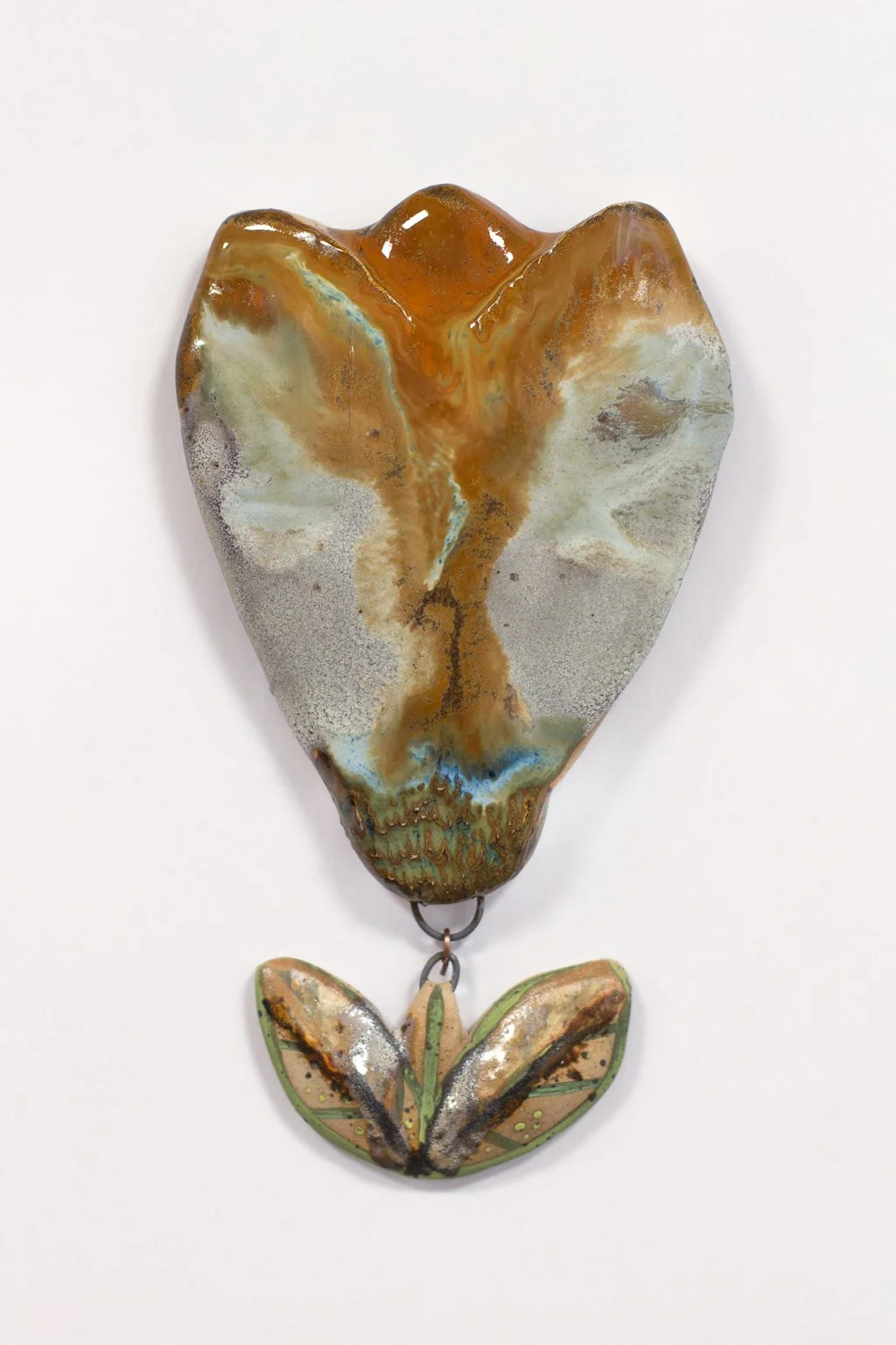 Kuvassa on taidokkaasti maalattu metalli- tai keramiikkamuotokuvan kaltainen taideteos, joka muistuttaa punaista ja vihreää kukkaa tai kasvia.