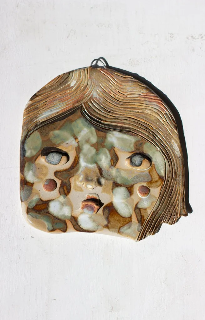 Reliefi kasvoista, on tehty kerroksellisista ja värillisistä materiaaleista.