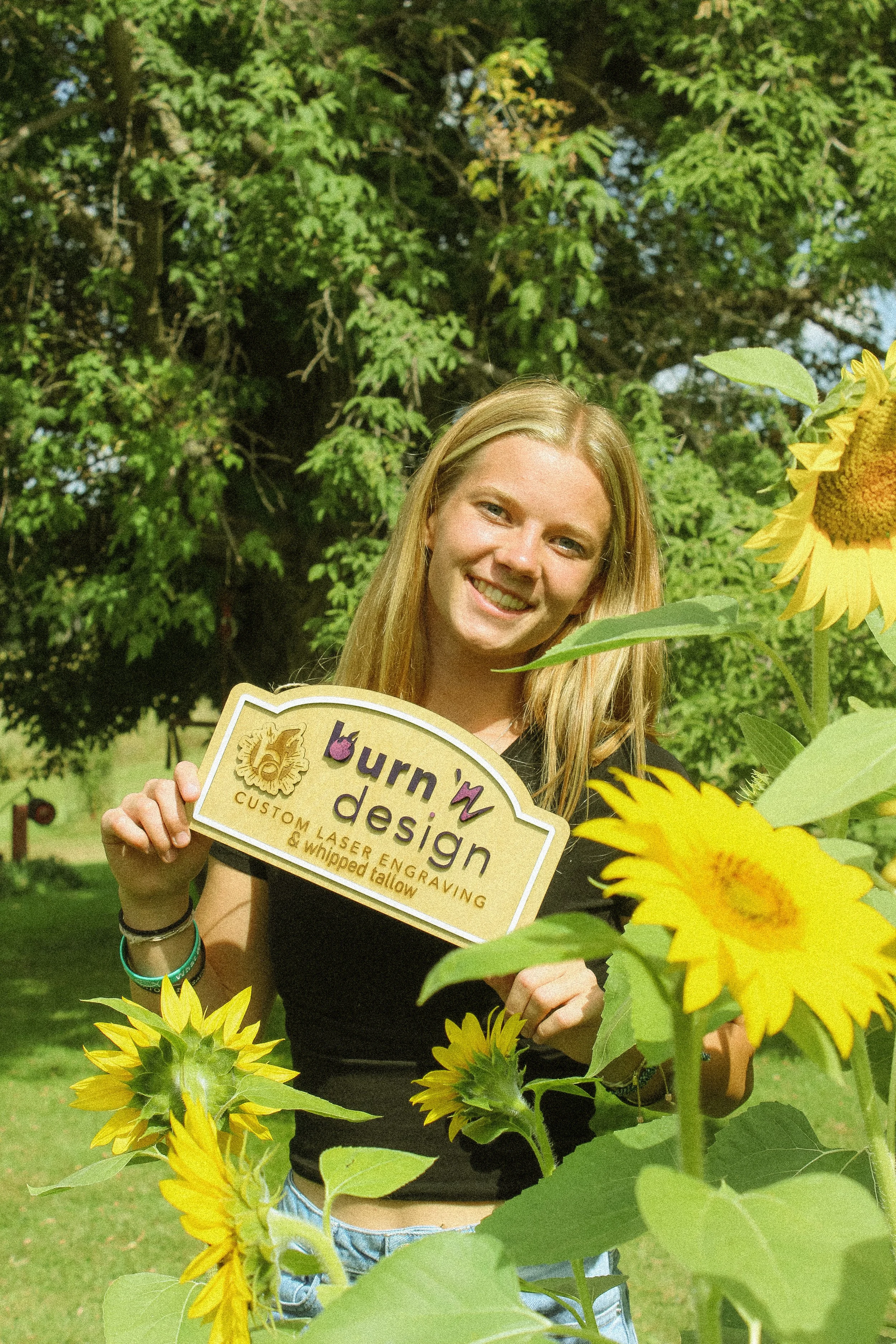 Creator & founder of Burn 'n Design, Lexi, holding a sign made for her business