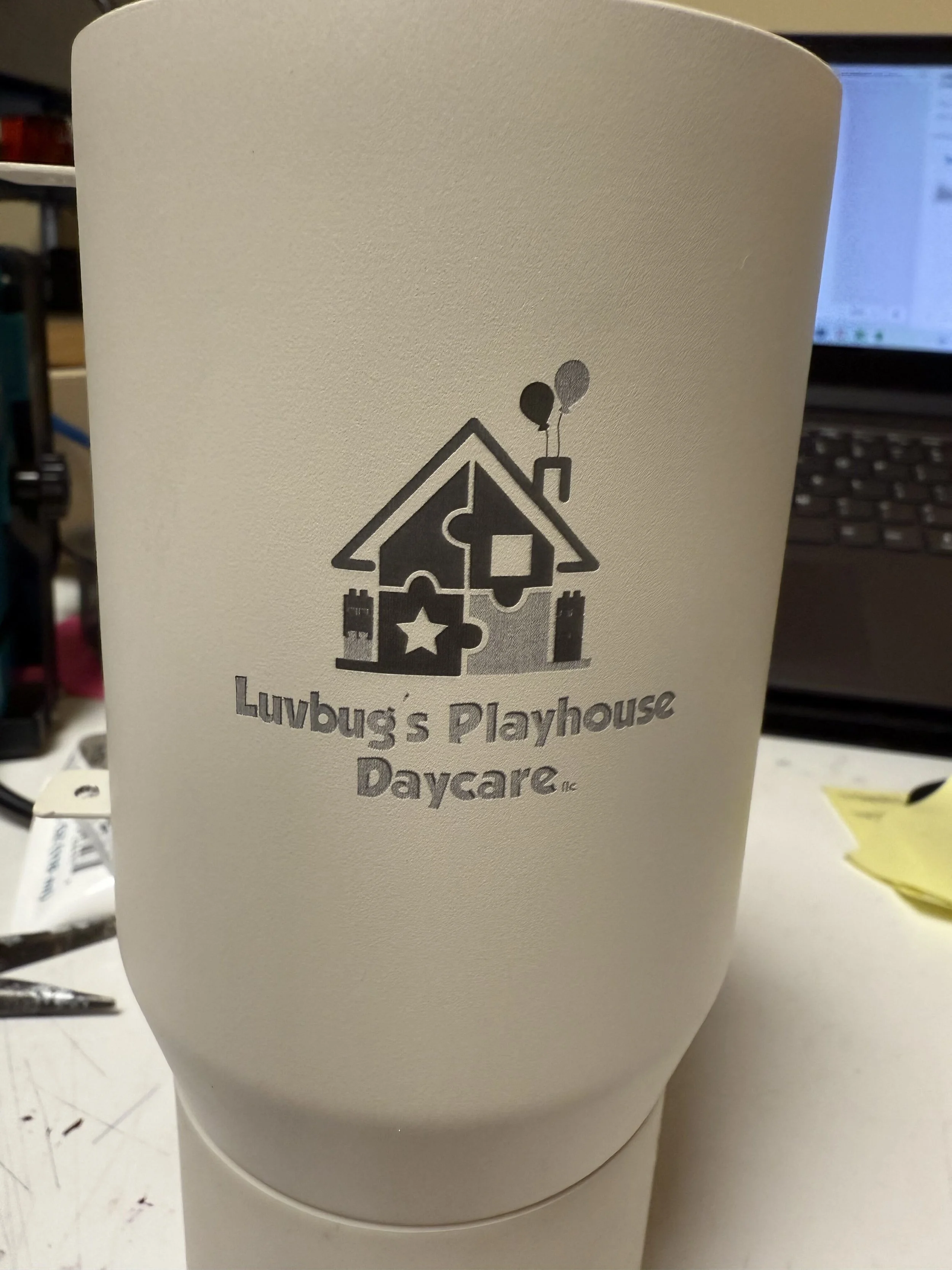 White tumbler with an engraved business logo. 